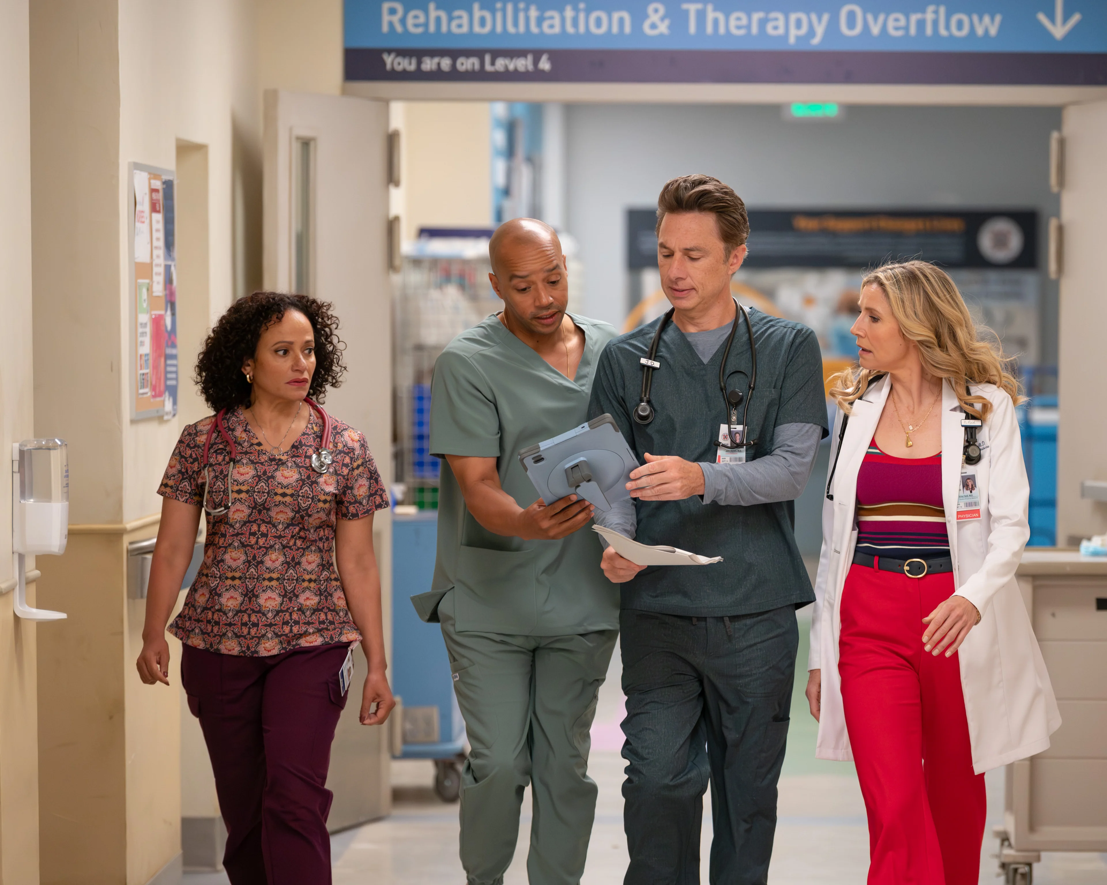 Ava Bunn, Donald Faison, Zach Braff and Sarah Chalke walk together in a Scrubs revival hospital scene.