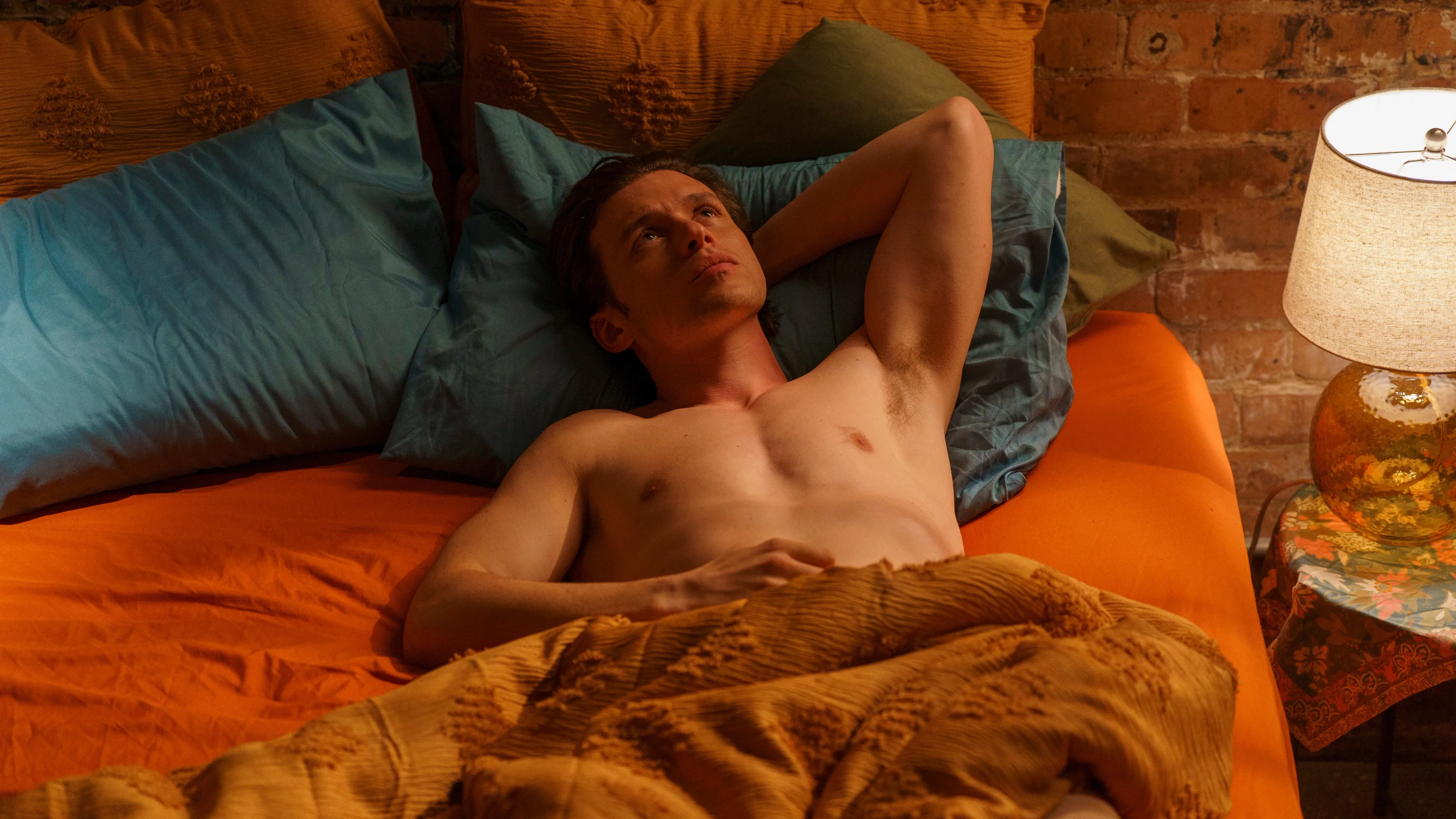 Charlie lies in bed with his hands behind his head.