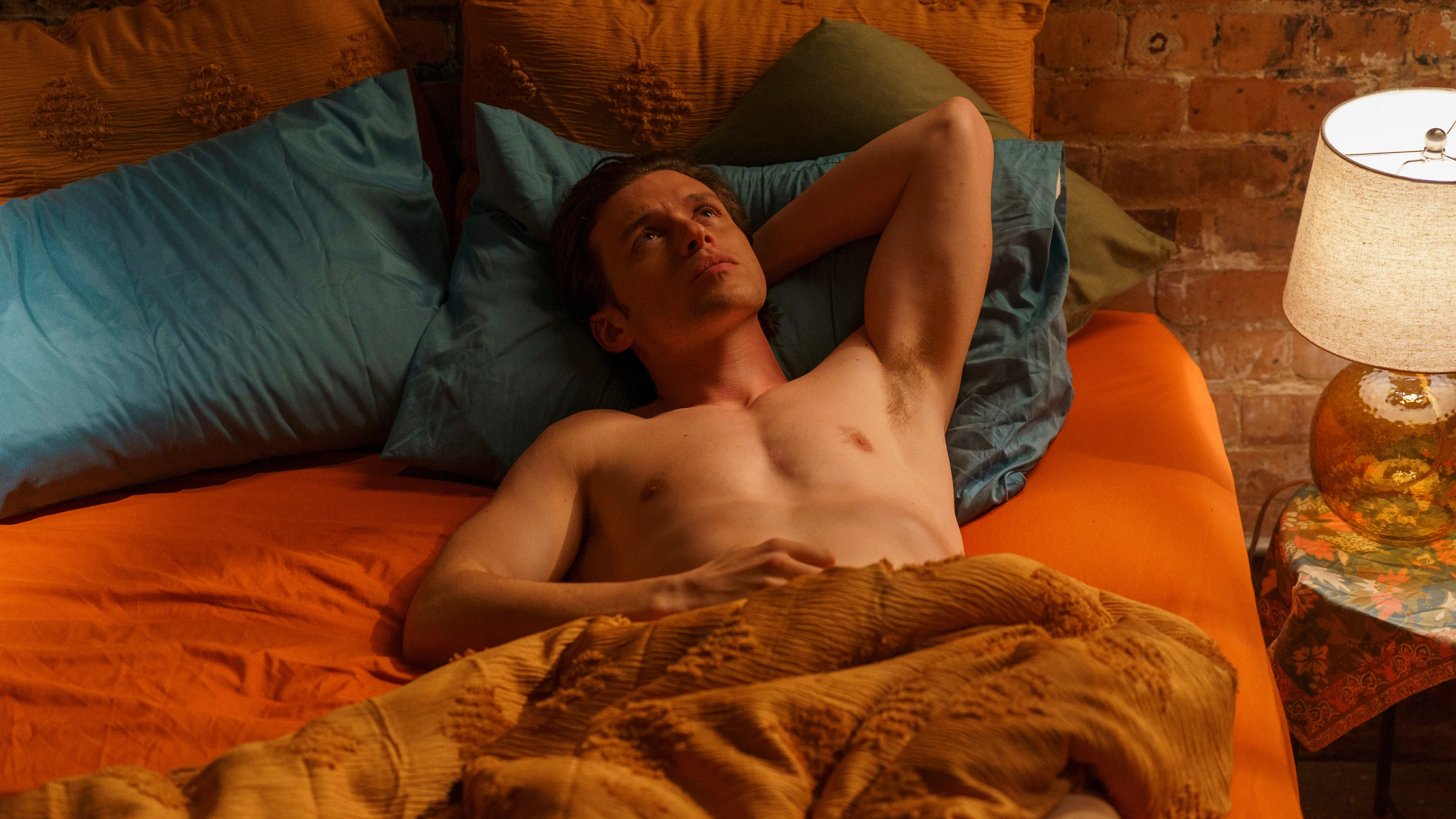 Charlie lies in bed with his hands behind his head.