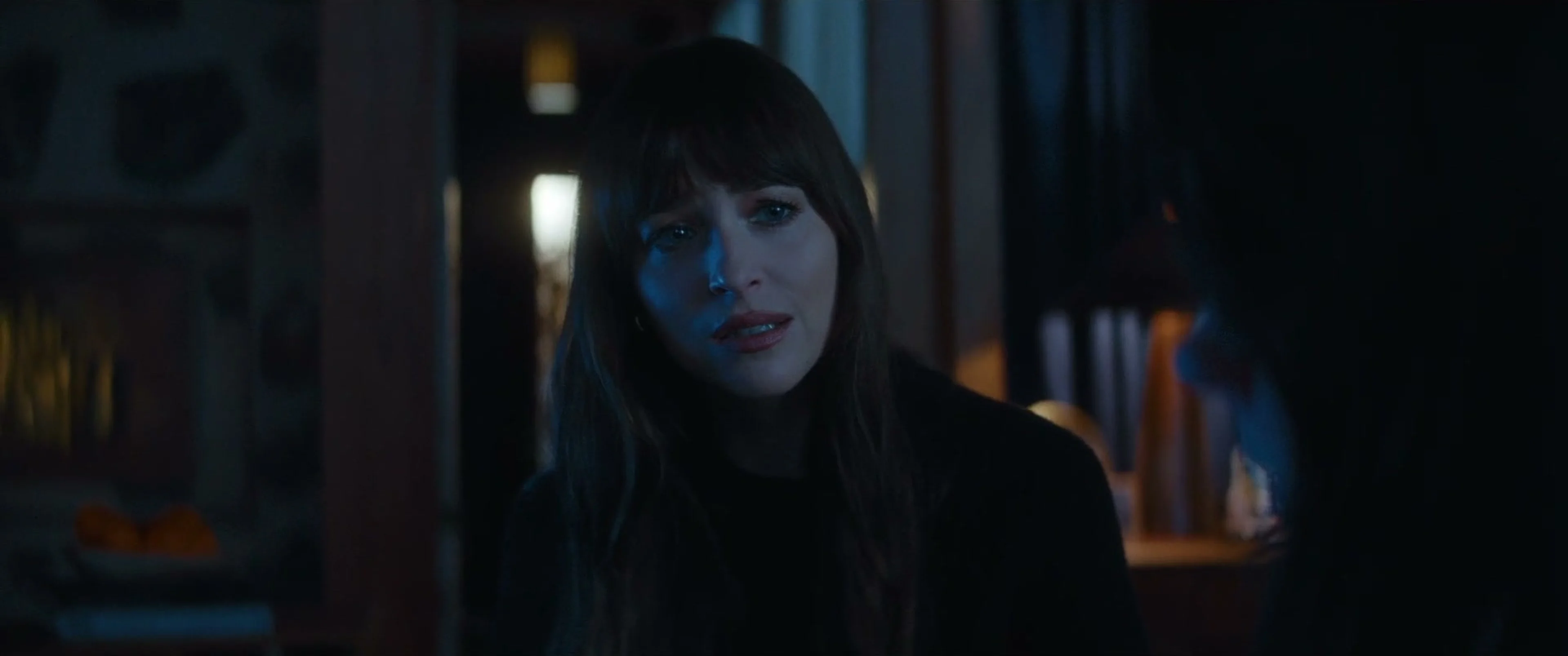 Lowen faces Verity in a dark room, with her mouth slightly open as she speaks.