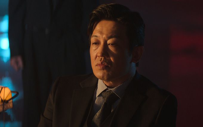 Heo Sung-tae sits in a dim room wearing a dark suit and tie.