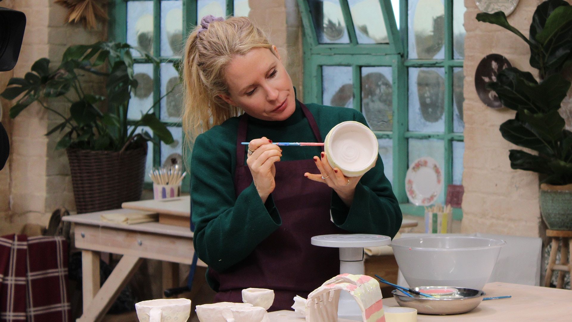 Lucy Beaumont paints a bowl while working on a clay breakfast set in the pottery.