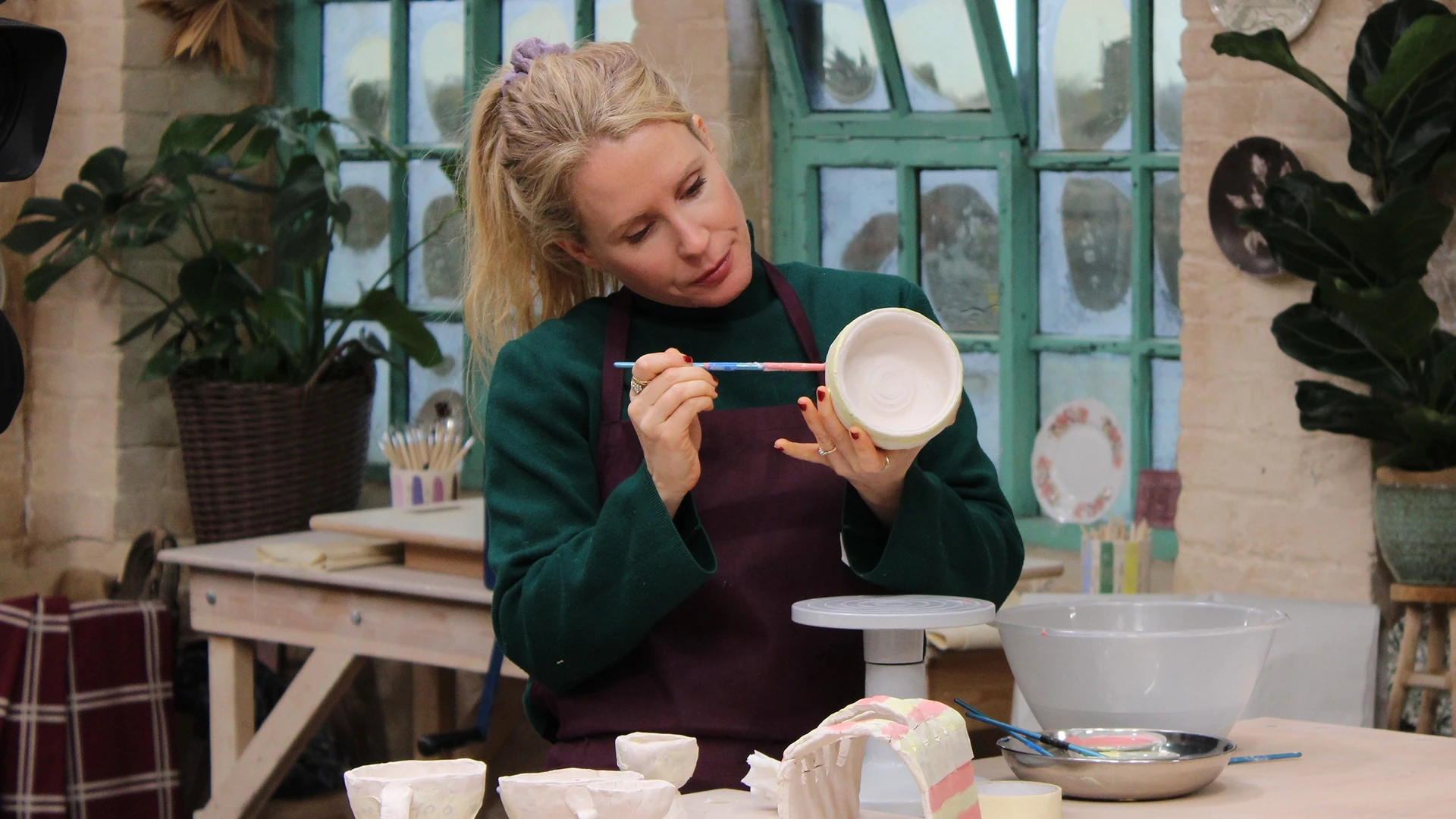 Lucy Beaumont paints a bowl while working on a clay breakfast set in the pottery.