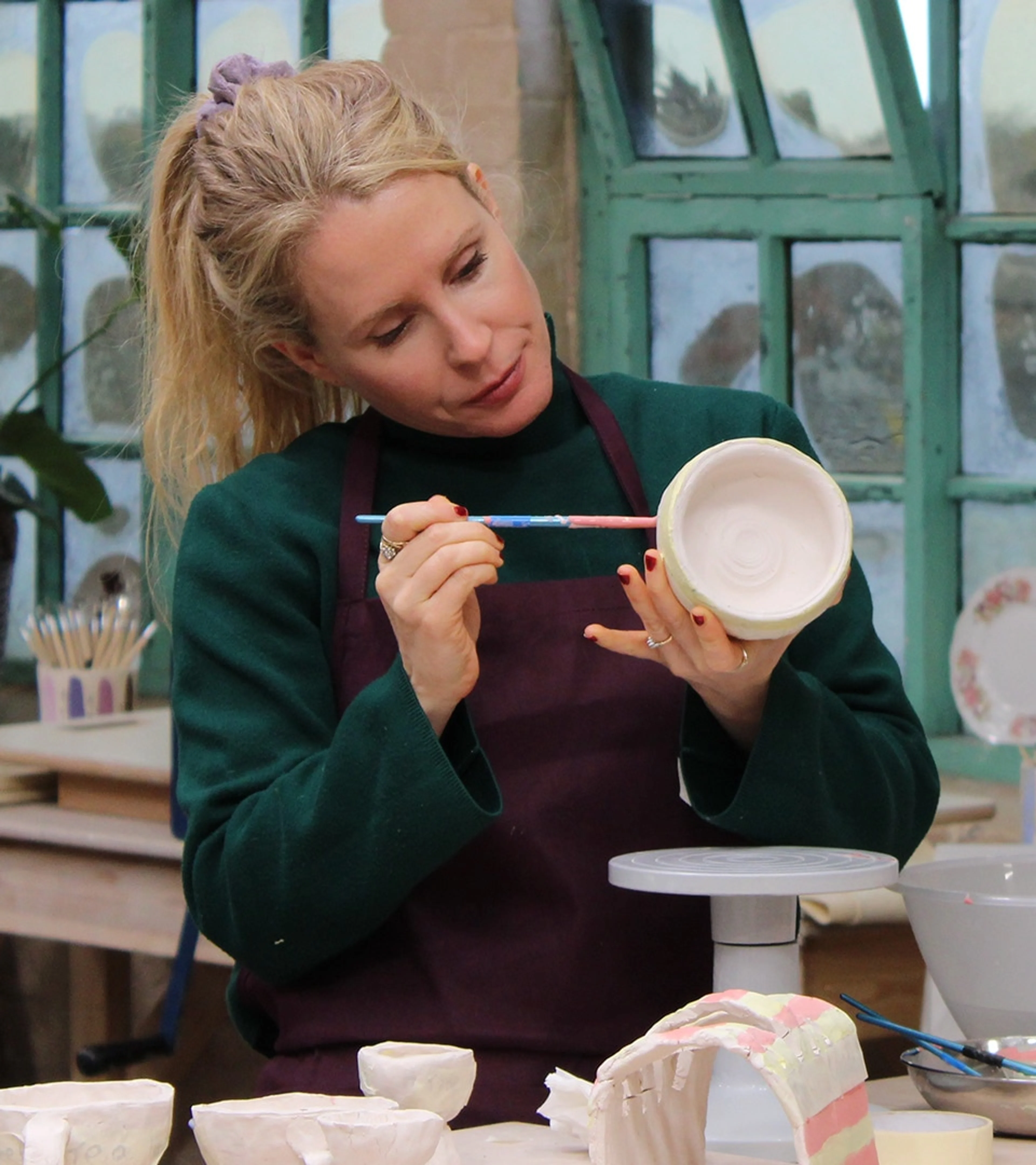 Lucy Beaumont paints a bowl while working on a clay breakfast set in the pottery.