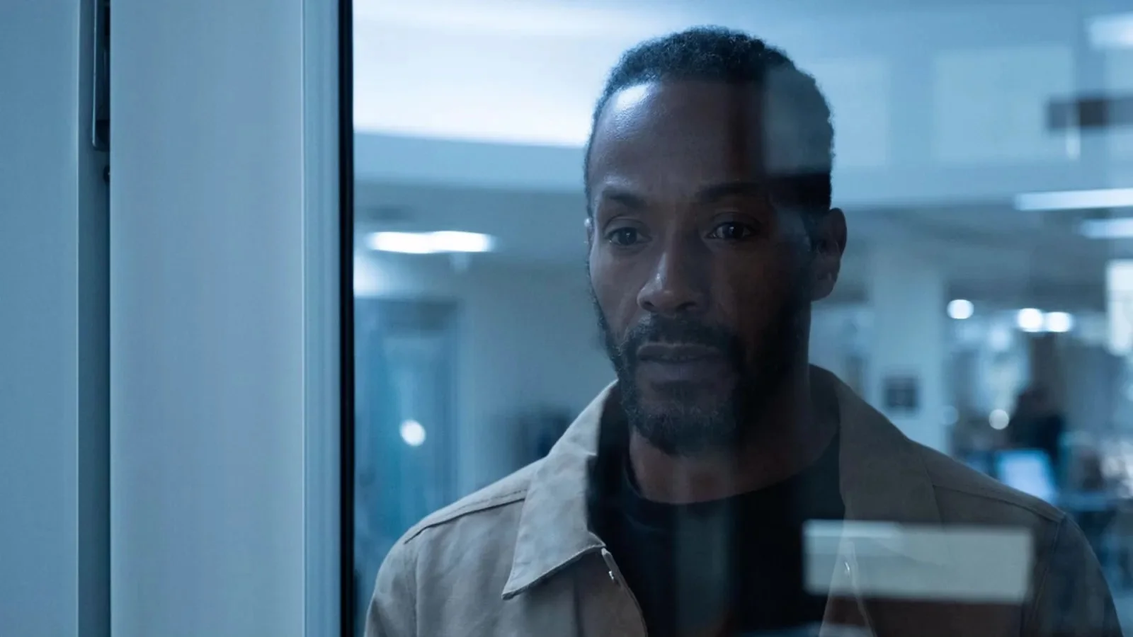 McKinley Freeman as Lewis Stewart stands behind a glass wall.