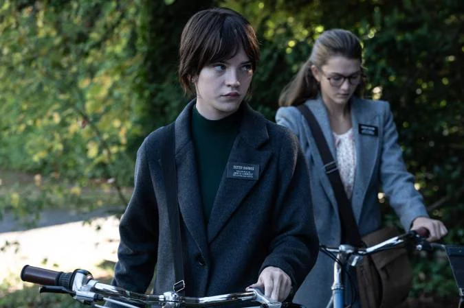 Barnes and Paxton stand outdoors beside their bicycles.