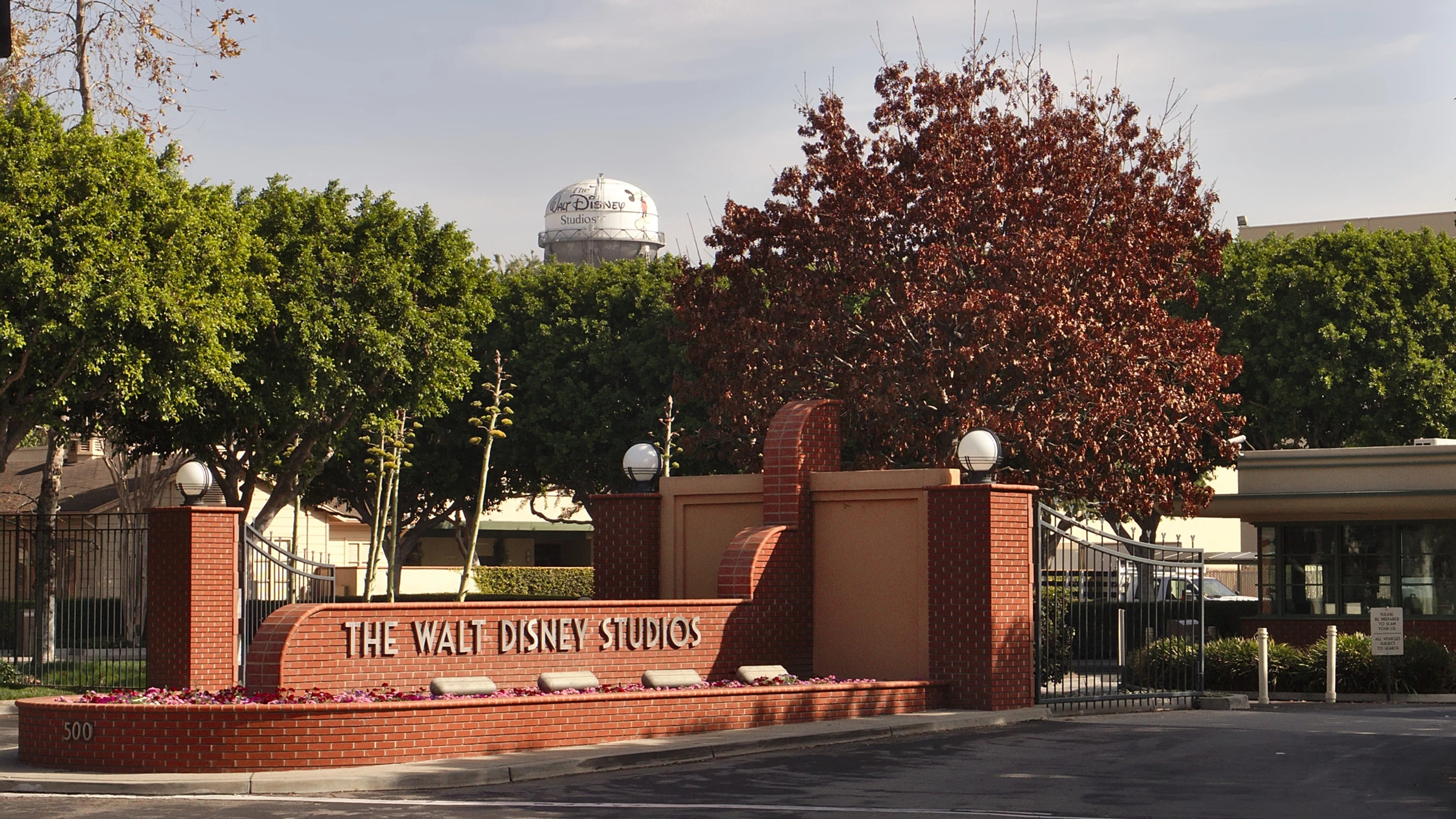 The Walt Disney Studios entrance and water tower stand behind trees in Burbank, California.