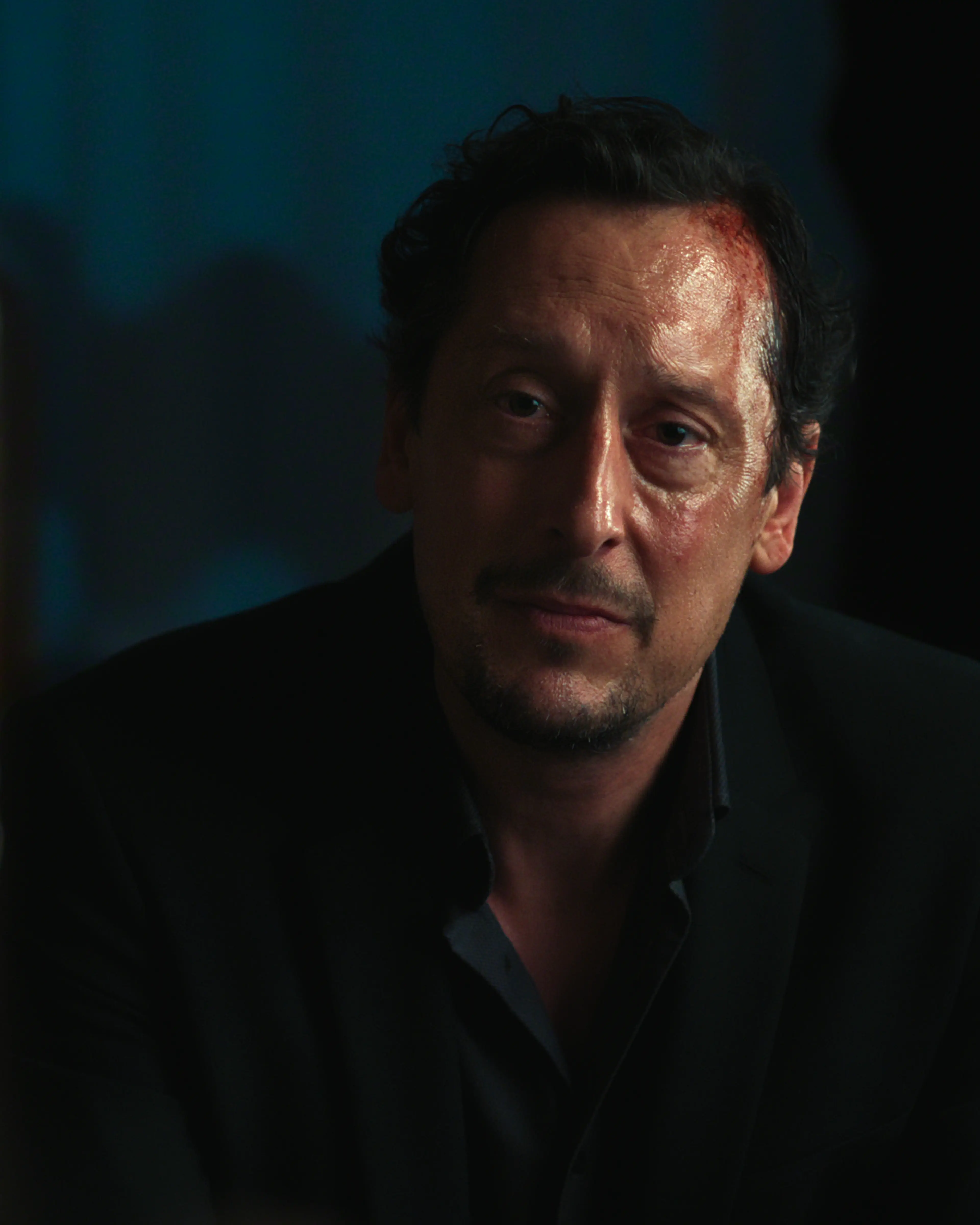 Hans Löw as Robert Lenzen sits opposite a woman in a dim room.