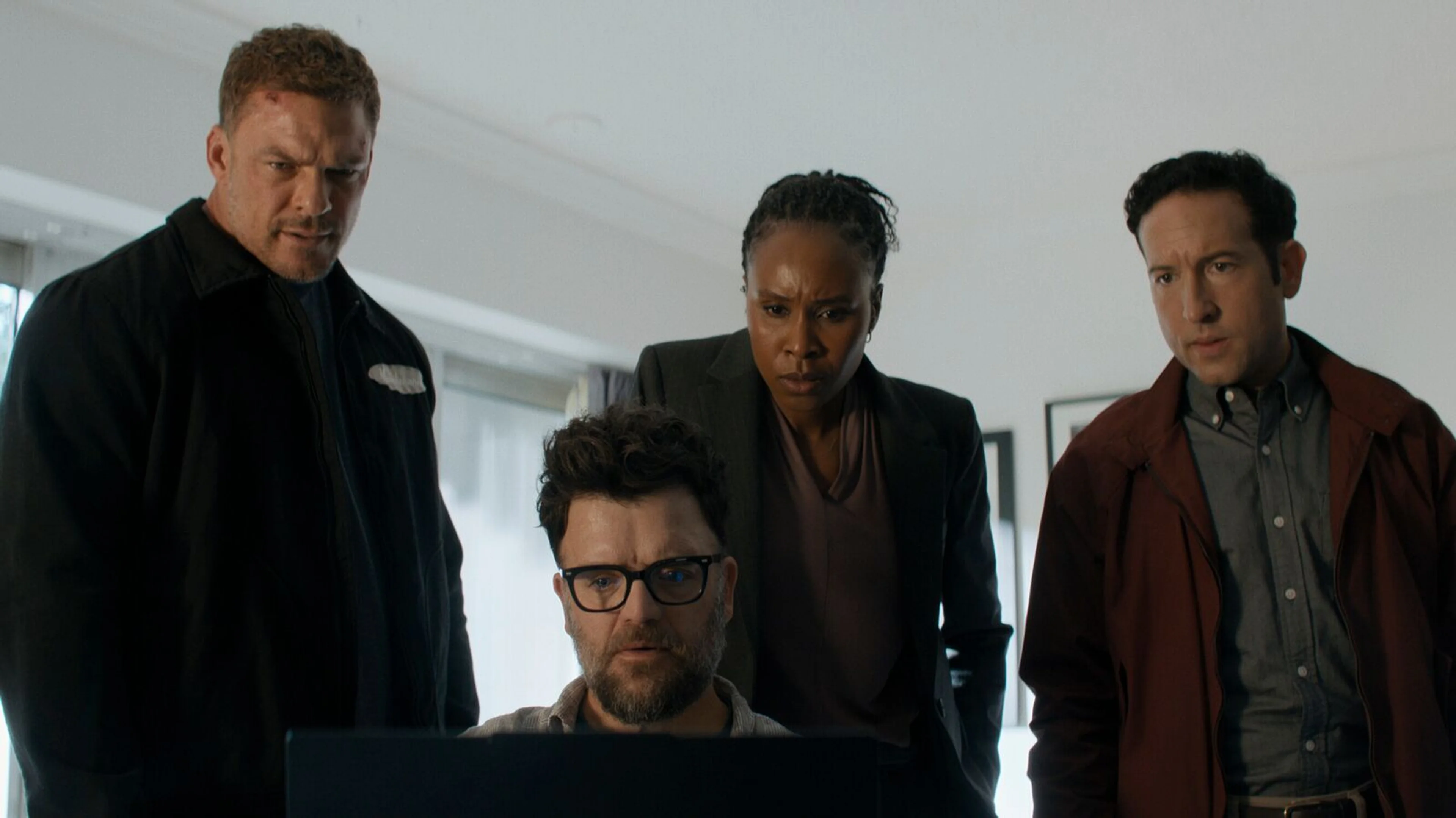 Alan Ritchson and the Reacher Season 4 cast gather around a laptop during an investigation.