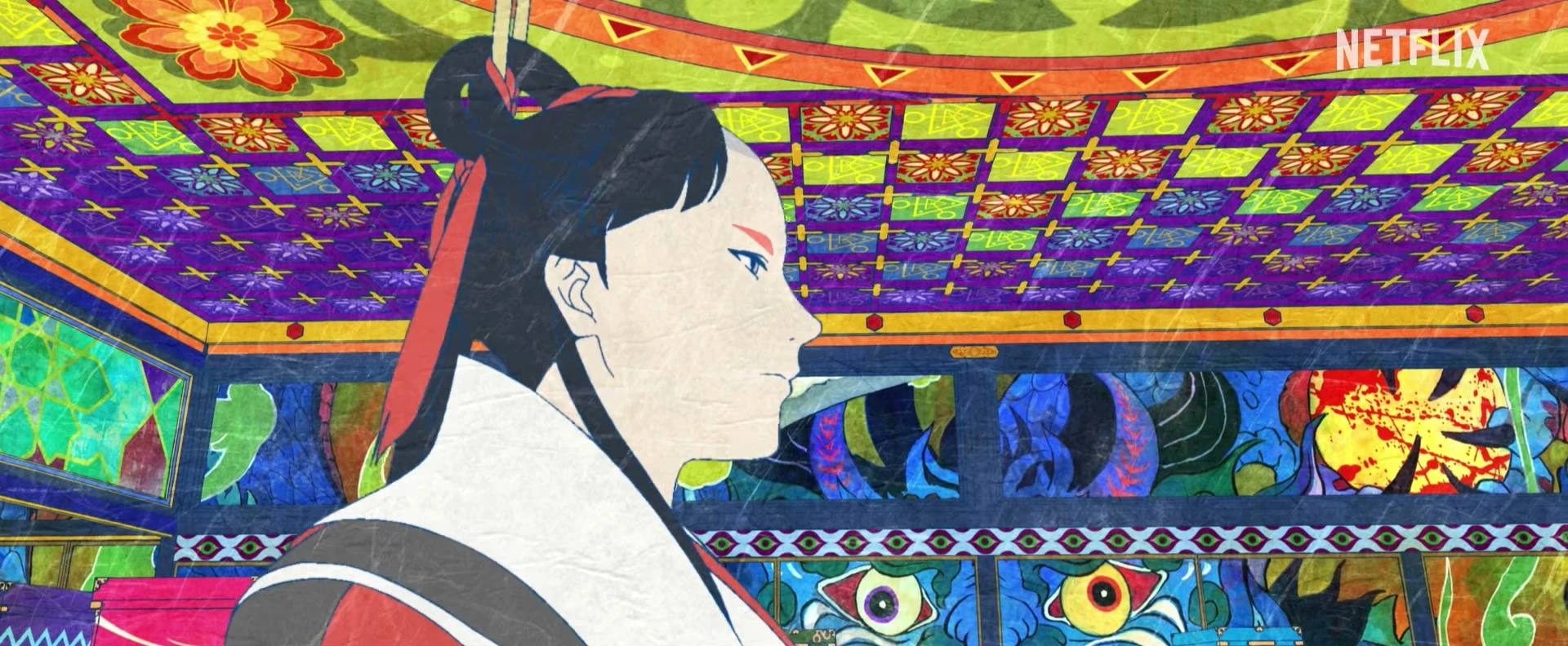 The Medicine Seller turns in front of a vividly patterned palace interior.