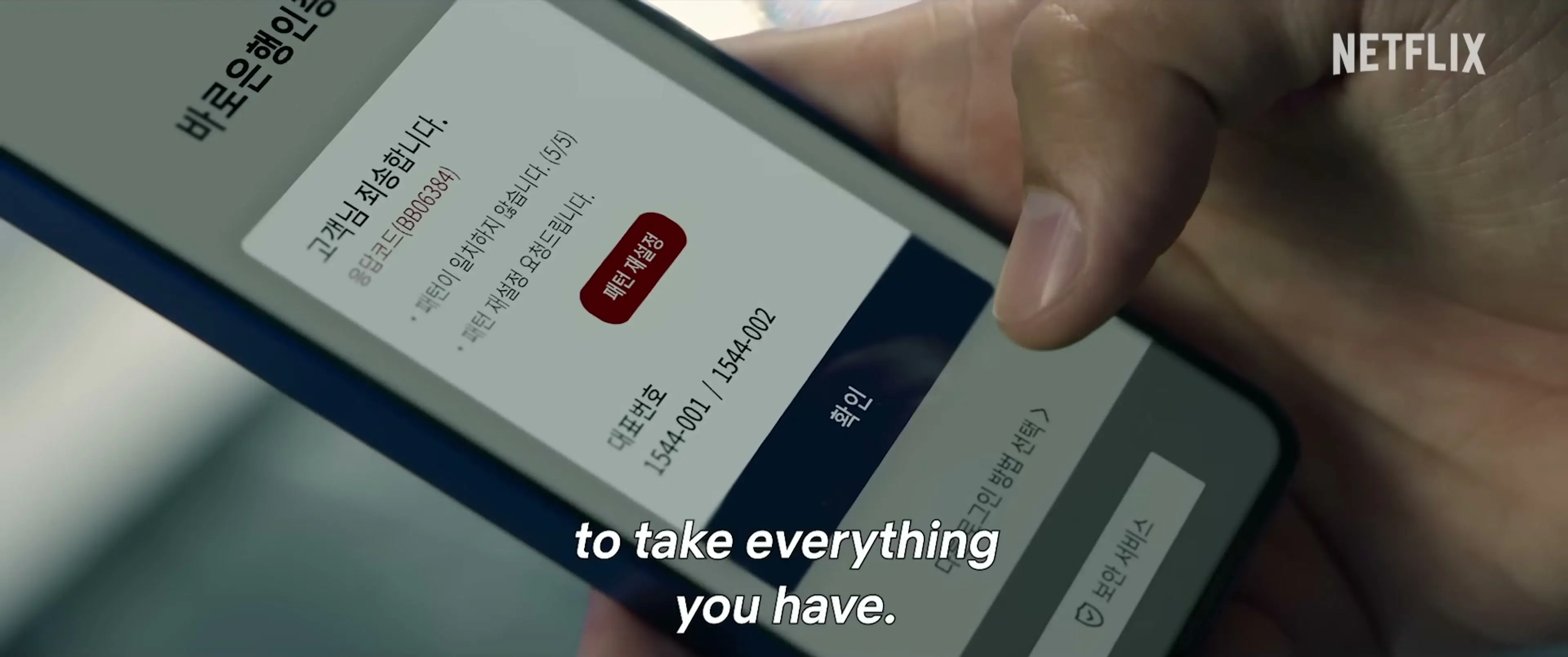 A hand holds a phone displaying a Korean banking screen in the official Mousetrap trailer.