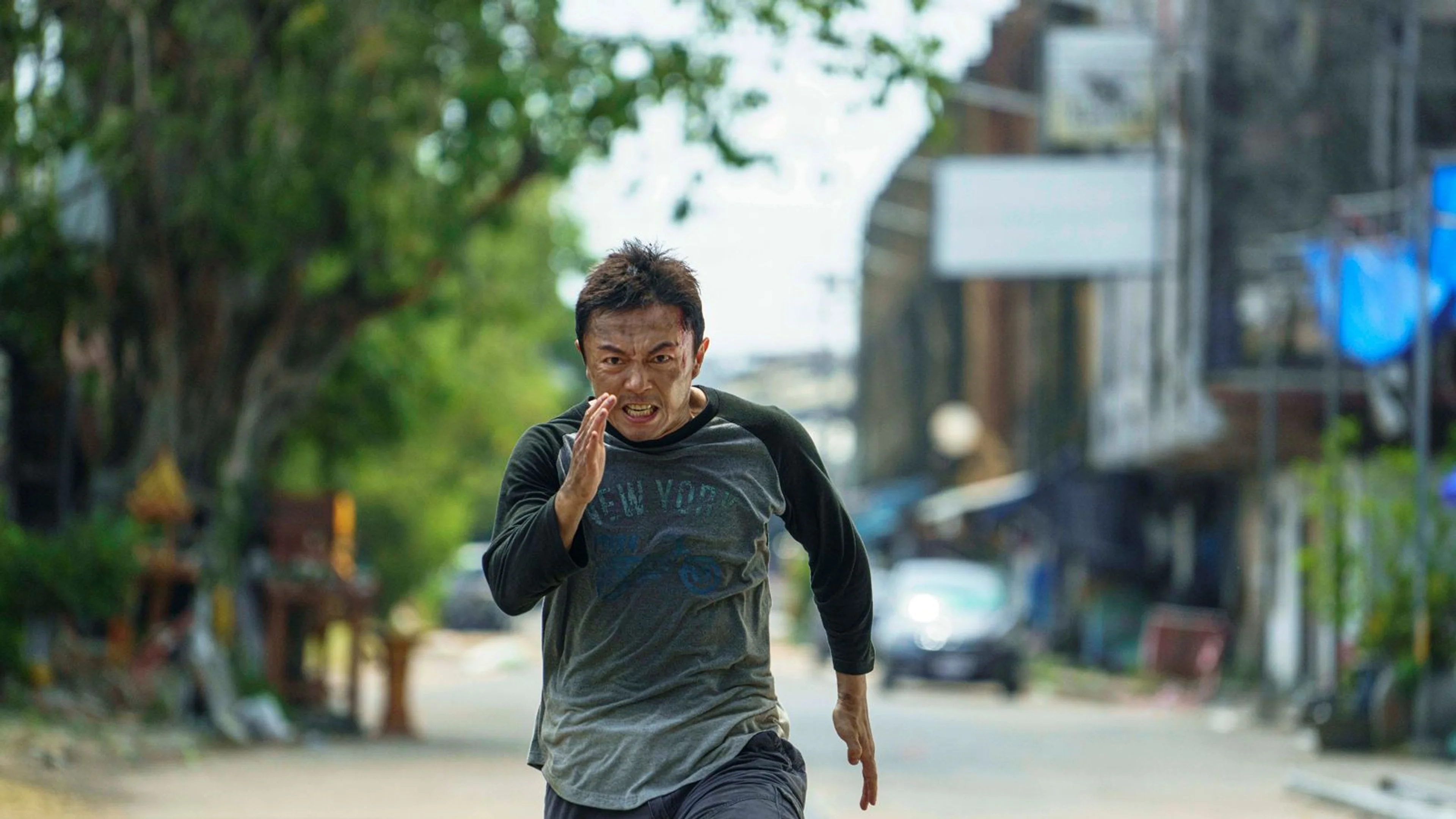 Wang Wei runs down a street in a gray and black shirt.