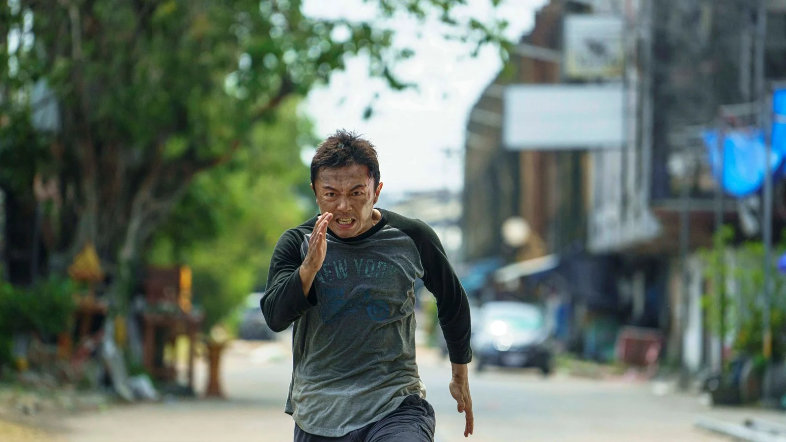 Wang Wei runs down a street in a gray and black shirt.