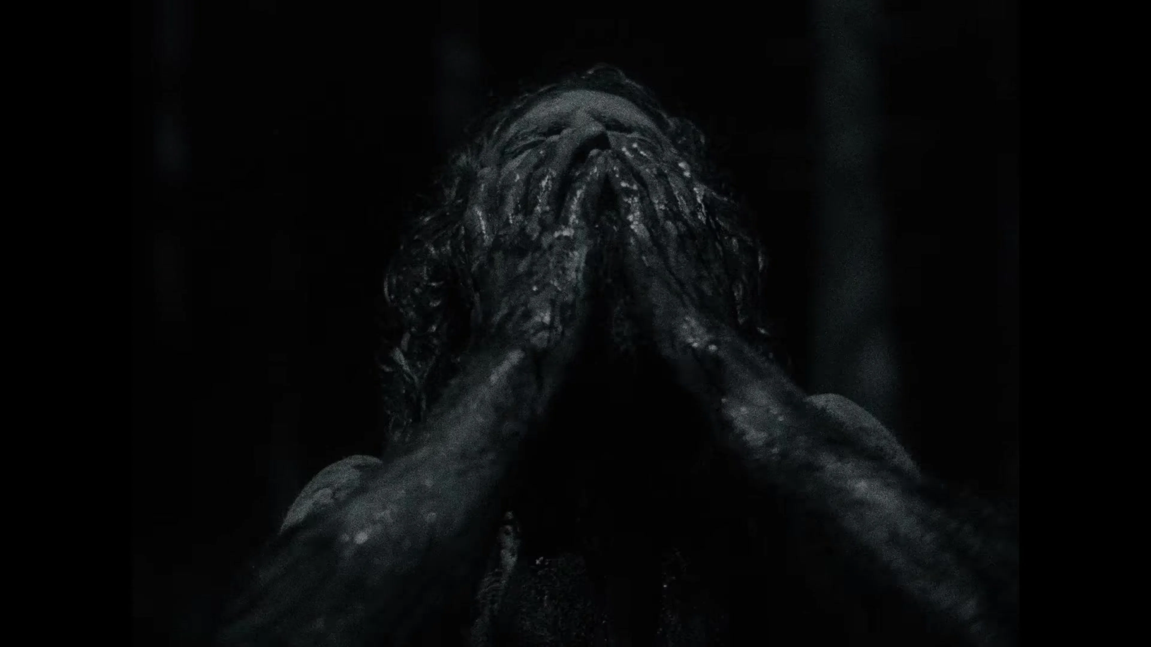 A figure covers a changing face with both hands in the Werwulf trailer.