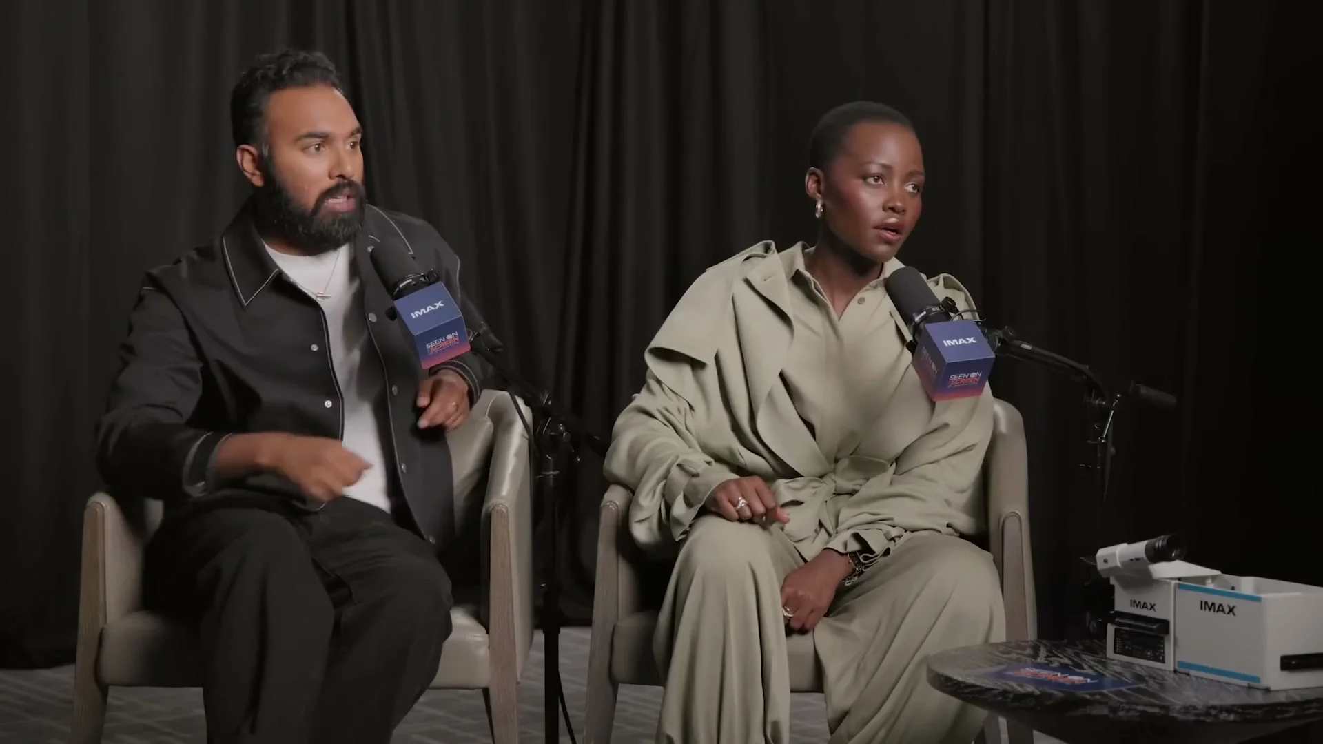 Himesh Patel and Lupita Nyong’o sit together during an interview about The Odyssey.