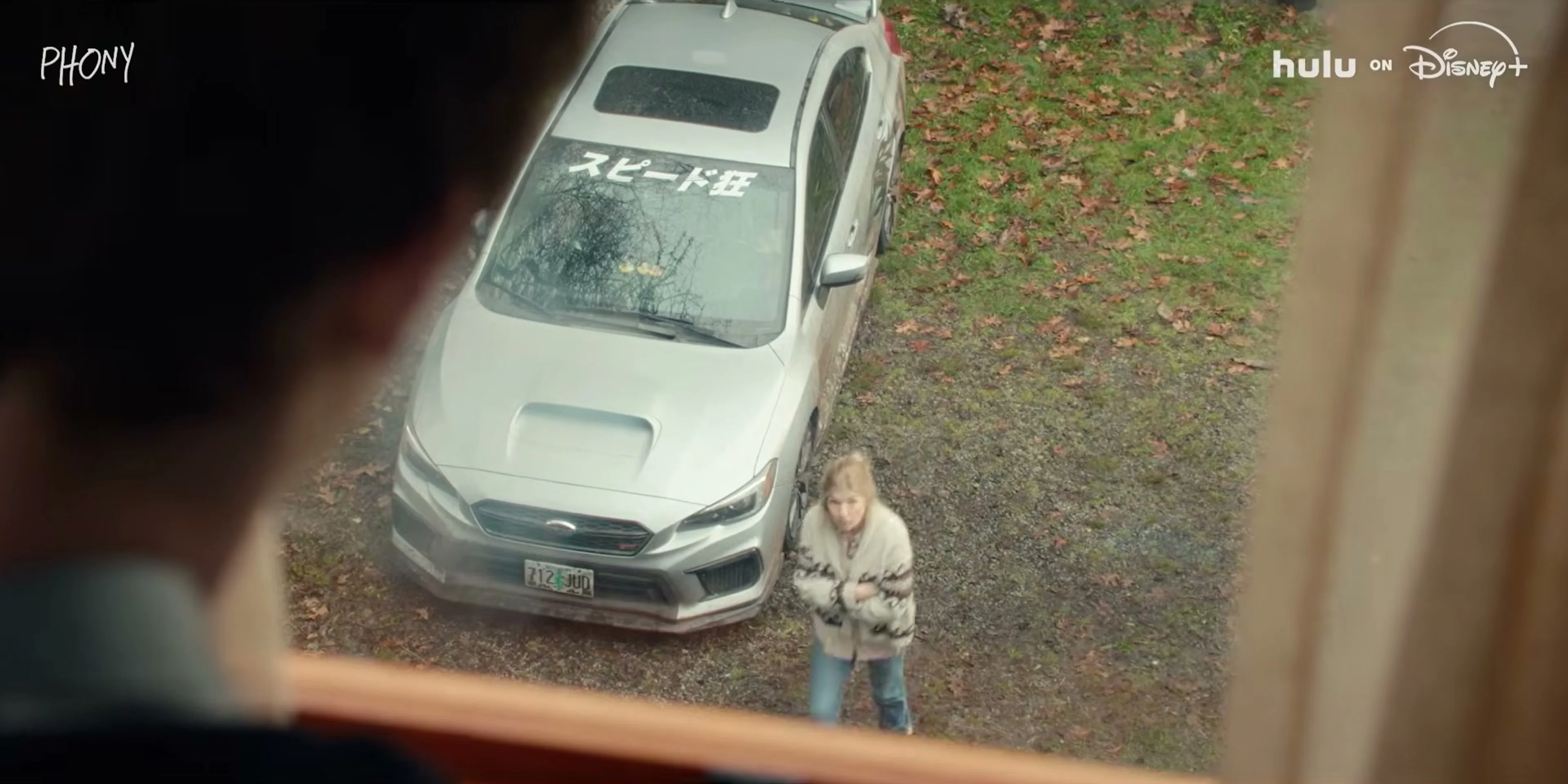 A woman stands near a car after an accident in the Phony trailer.