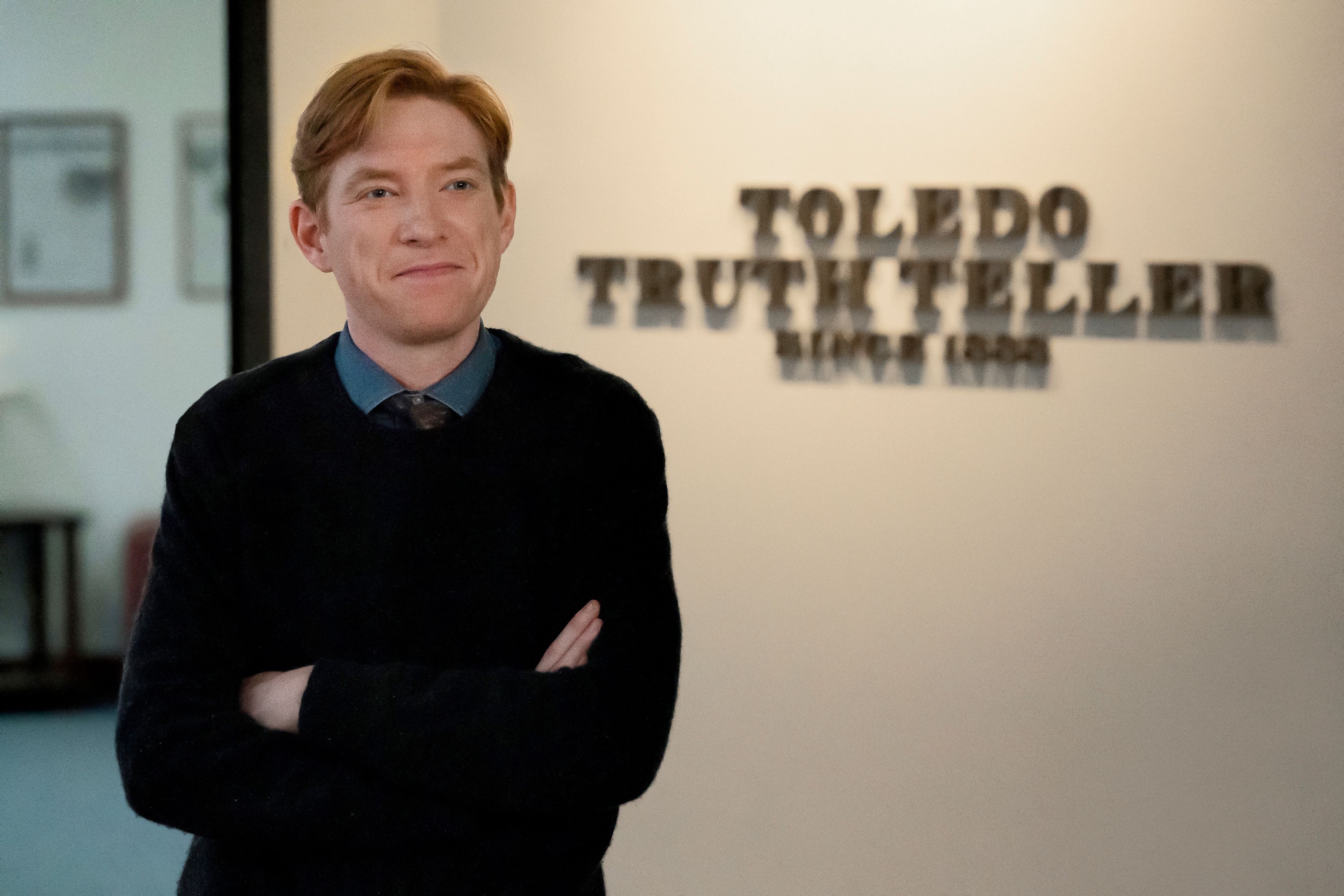 Ned Sampson stands with his arms folded beside the Toledo Truth Teller sign.