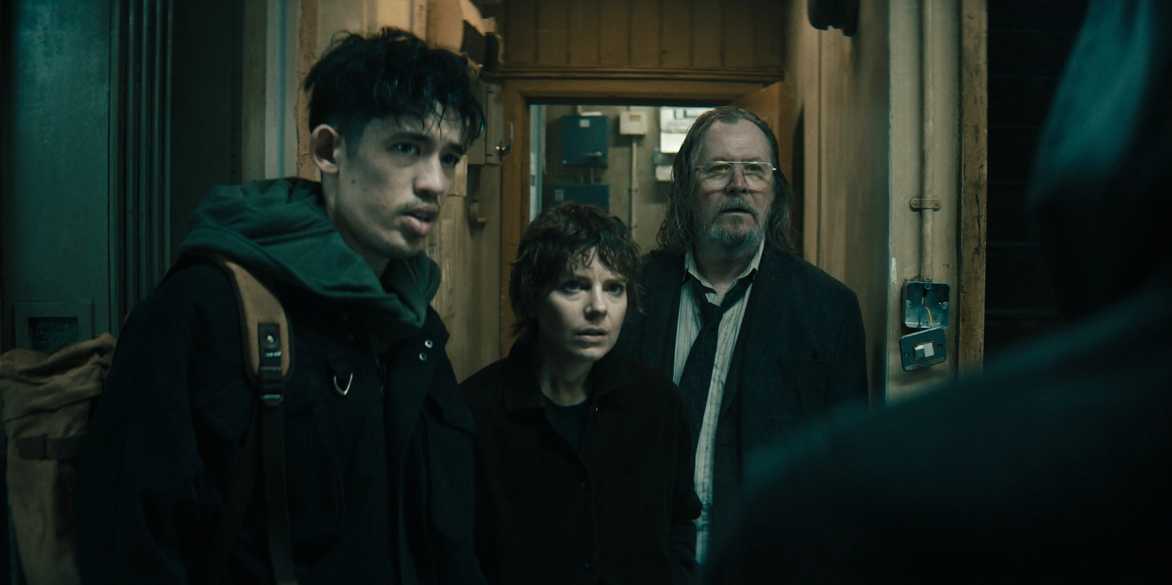Roddy Ho, Shirley Dander and Jackson Lamb stand together inside a narrow doorway.