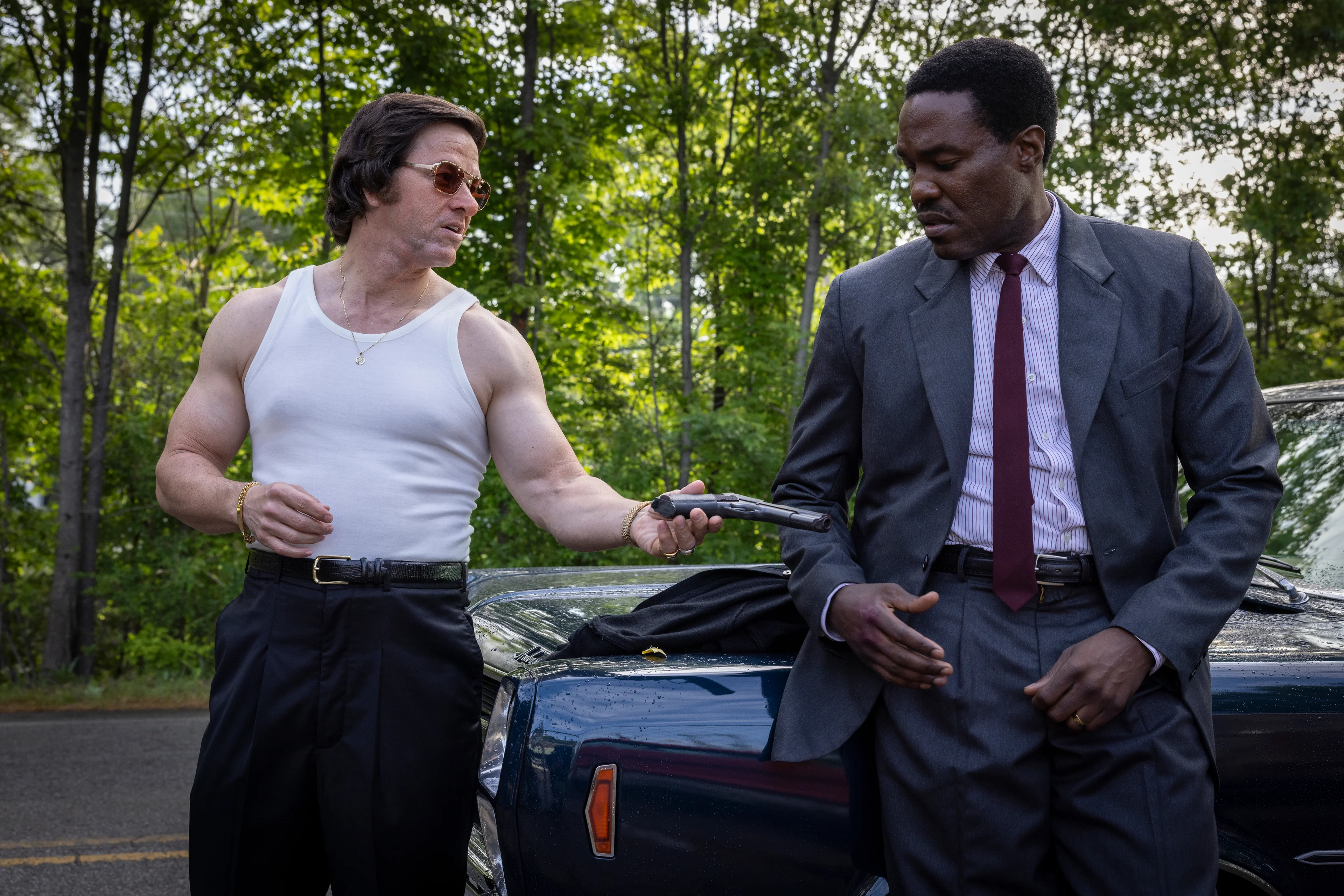 Greg Scarpa offers a handgun to Wayne Strider beside a car in By Any Means.