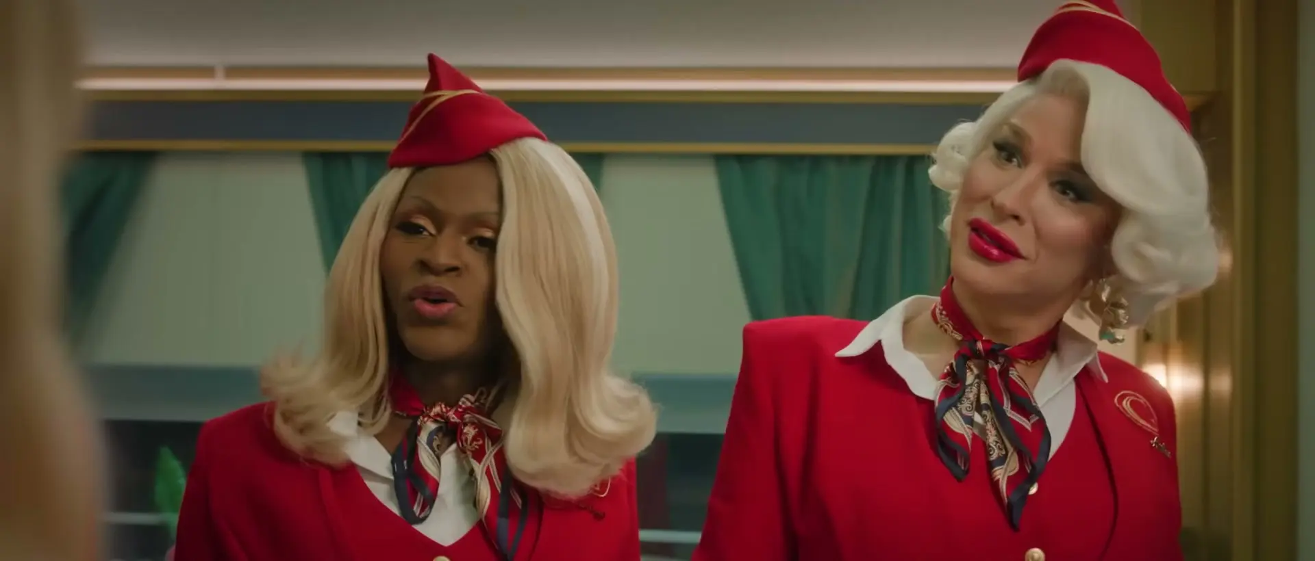 Two stewardesses in red Glamazonian Express uniforms face someone on their train.
