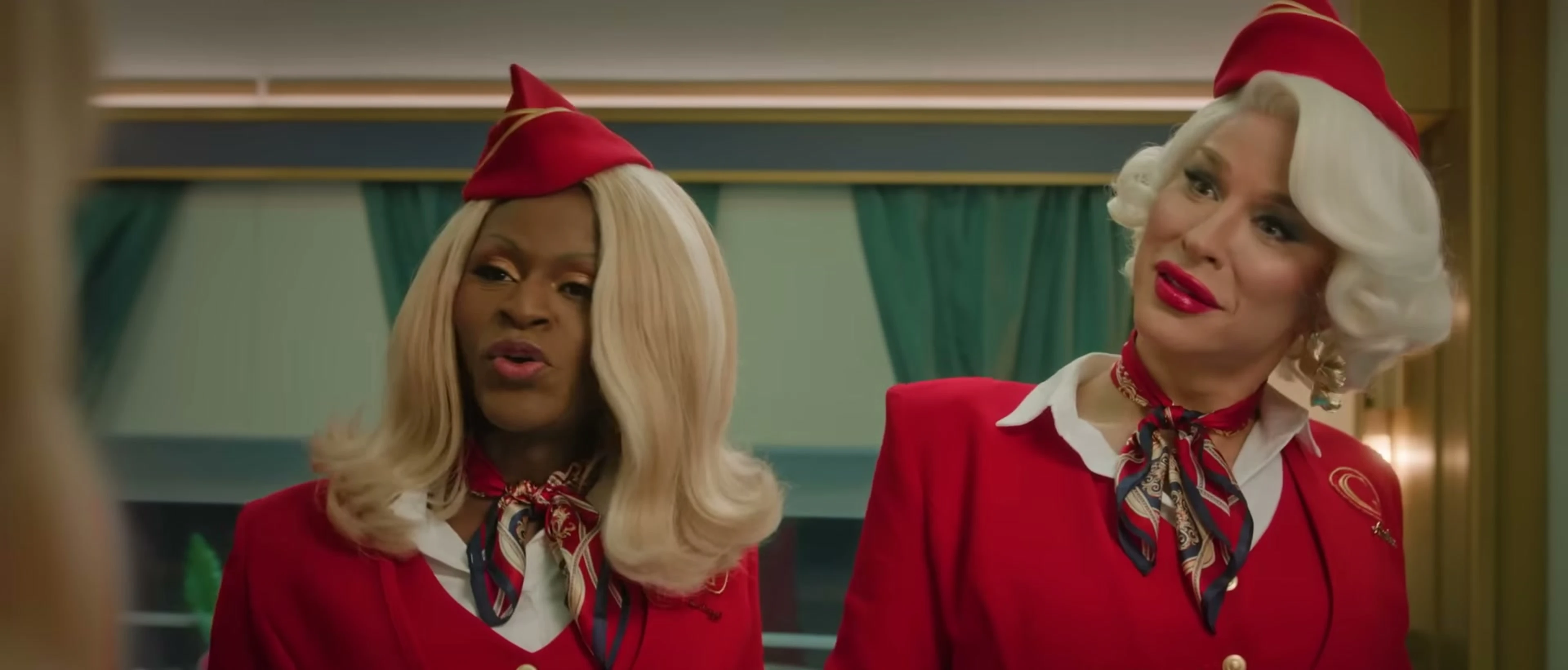 Two stewardesses in red Glamazonian Express uniforms face someone on their train.