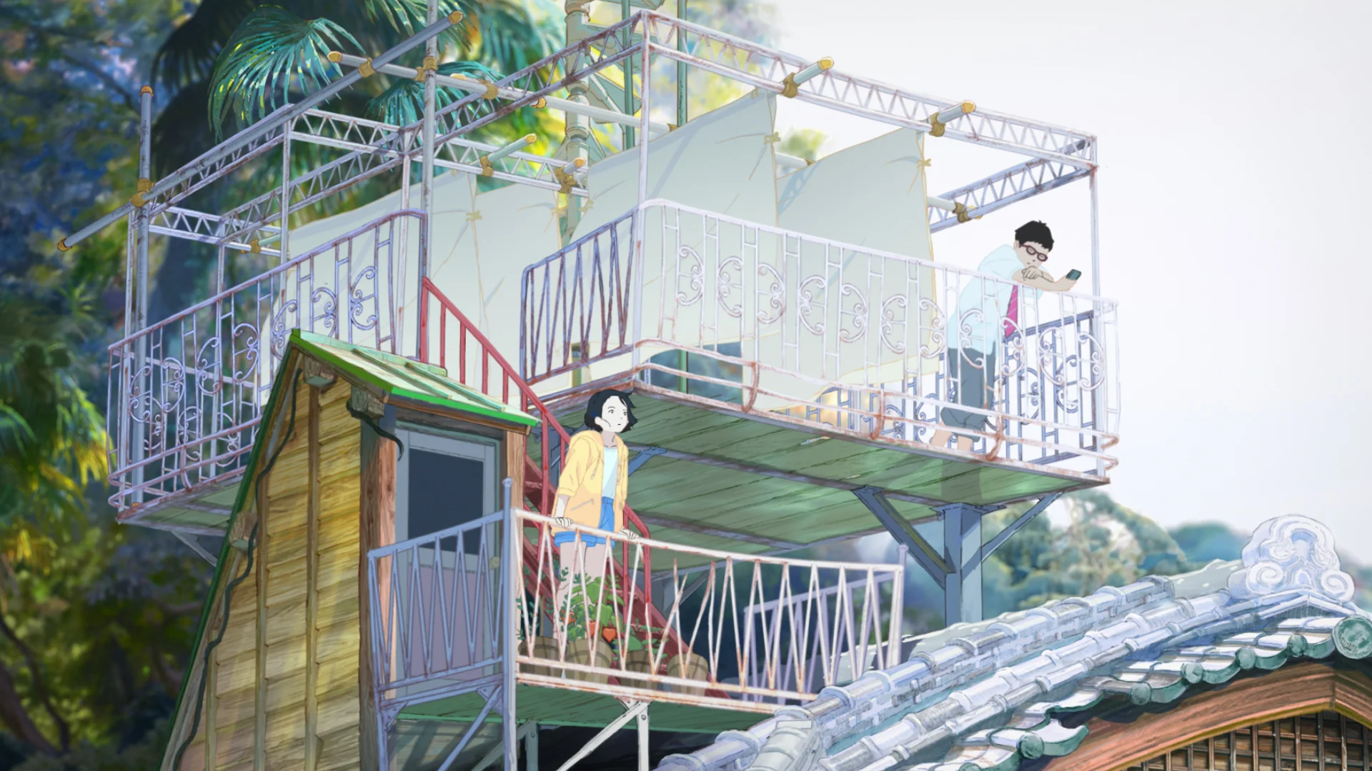 A multilevel building has wooden balconies, metal railings and a tiled roof beside thick greenery.