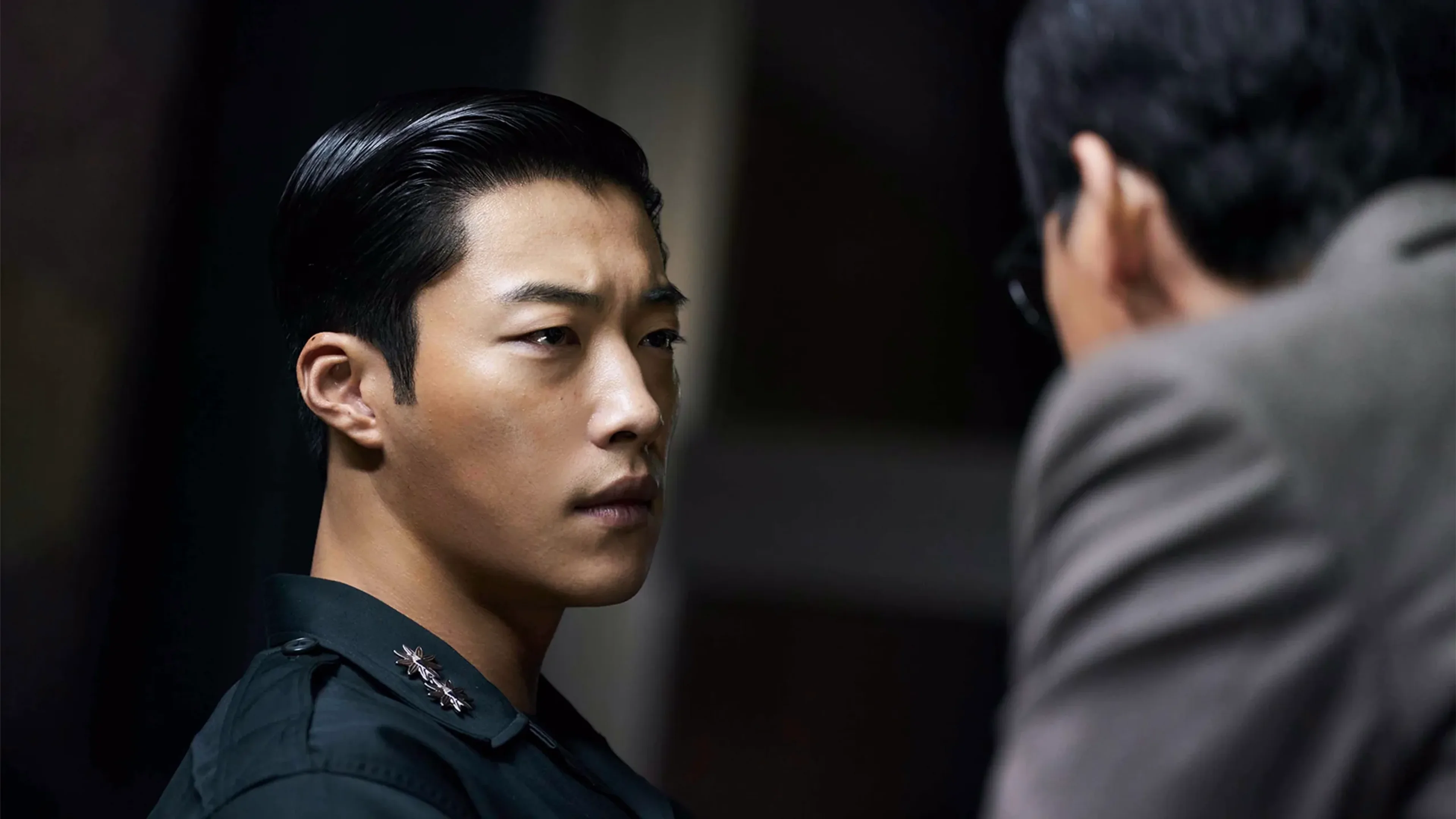 Woo Do-hwan as Ki-hyun looks toward another man while wearing a dark military uniform.