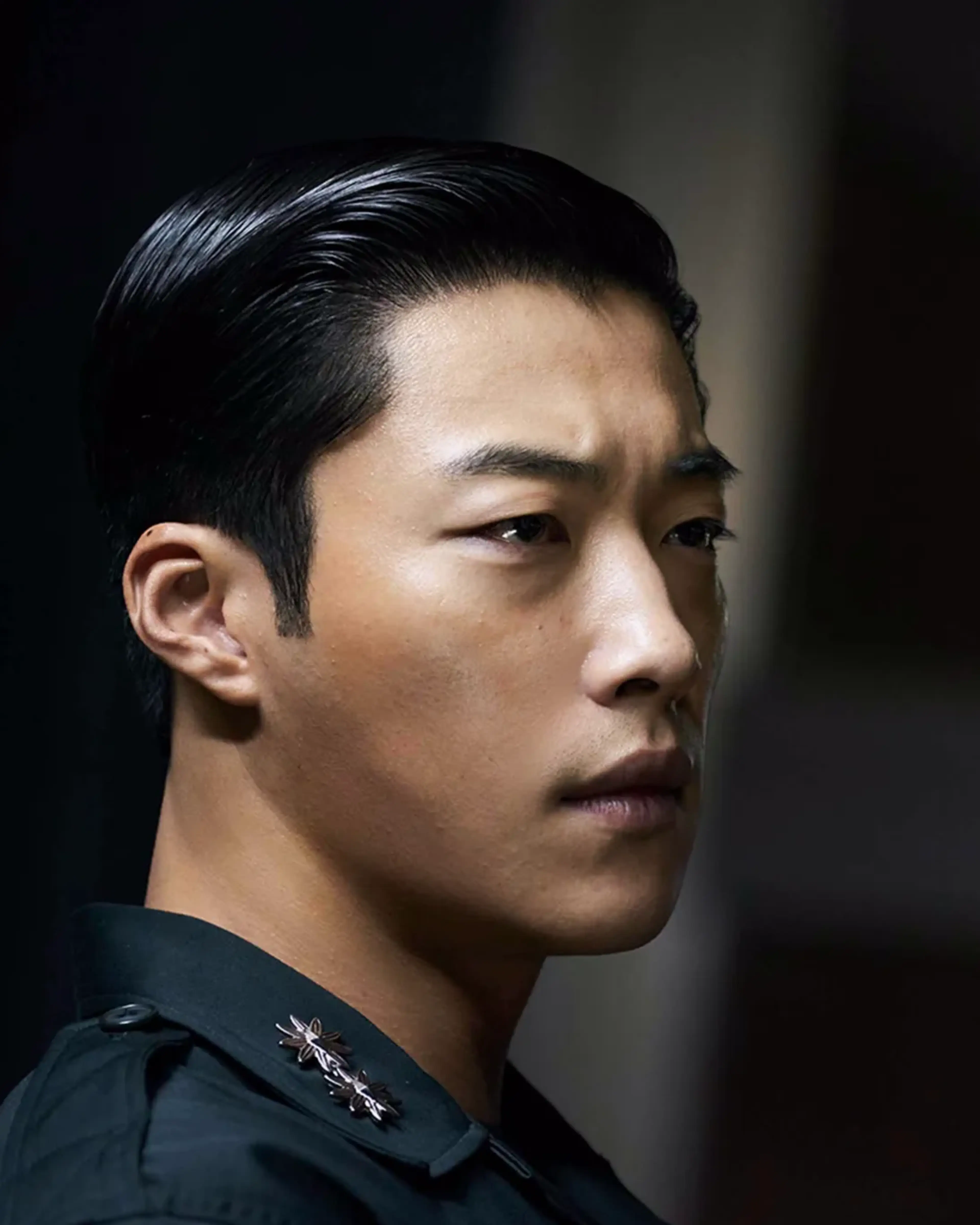 Woo Do-hwan as Ki-hyun looks toward another man while wearing a dark military uniform.