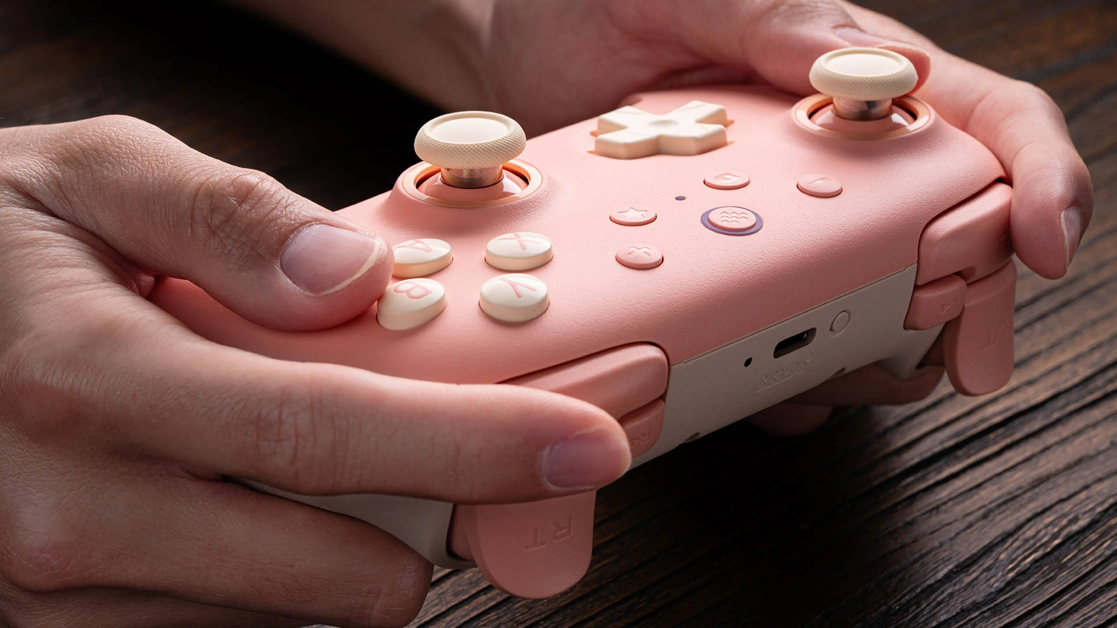 Peach Ultimate 2C Wireless held at an angle showing its top buttons and USB-C port