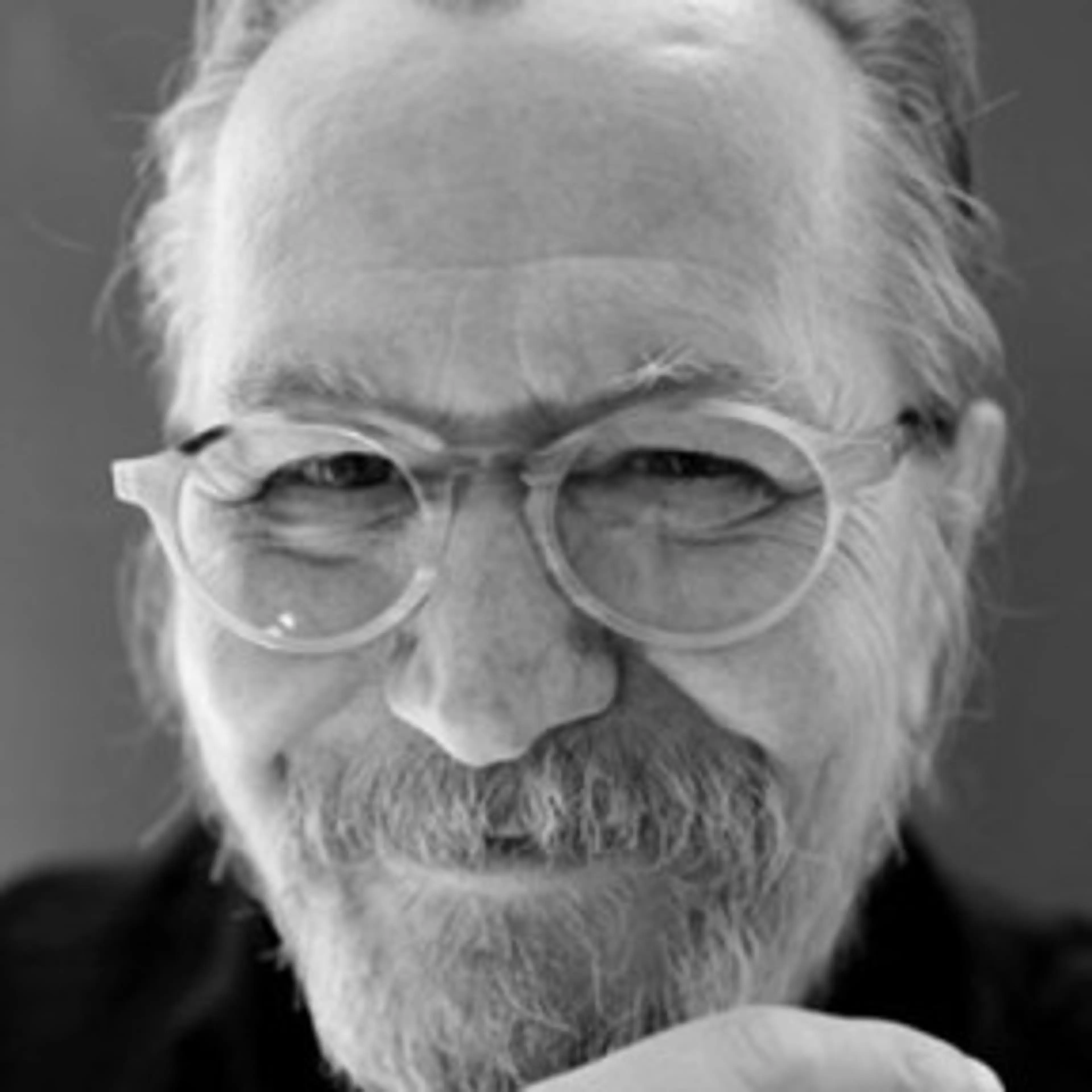 Black-and-white portrait of Gary Oldman smiling with glasses and a beard.