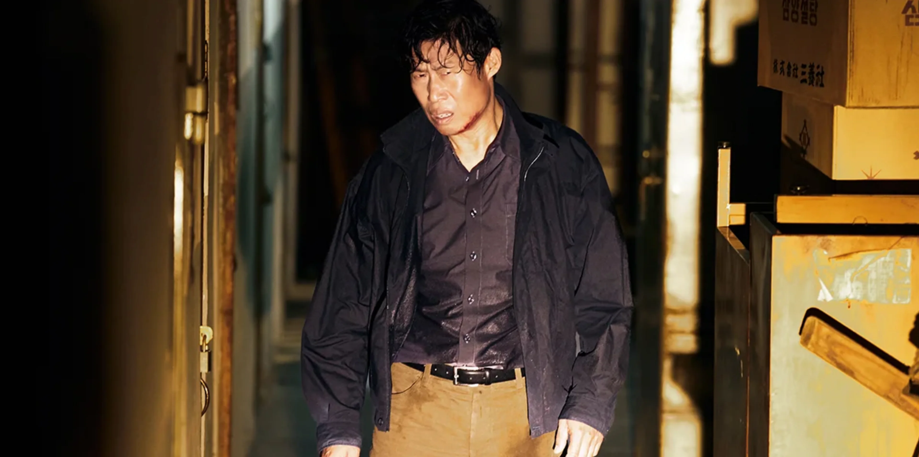 Yoo Hae-jin as detective Cheol-gu, with visible injuries, stands beside stacked boxes.
