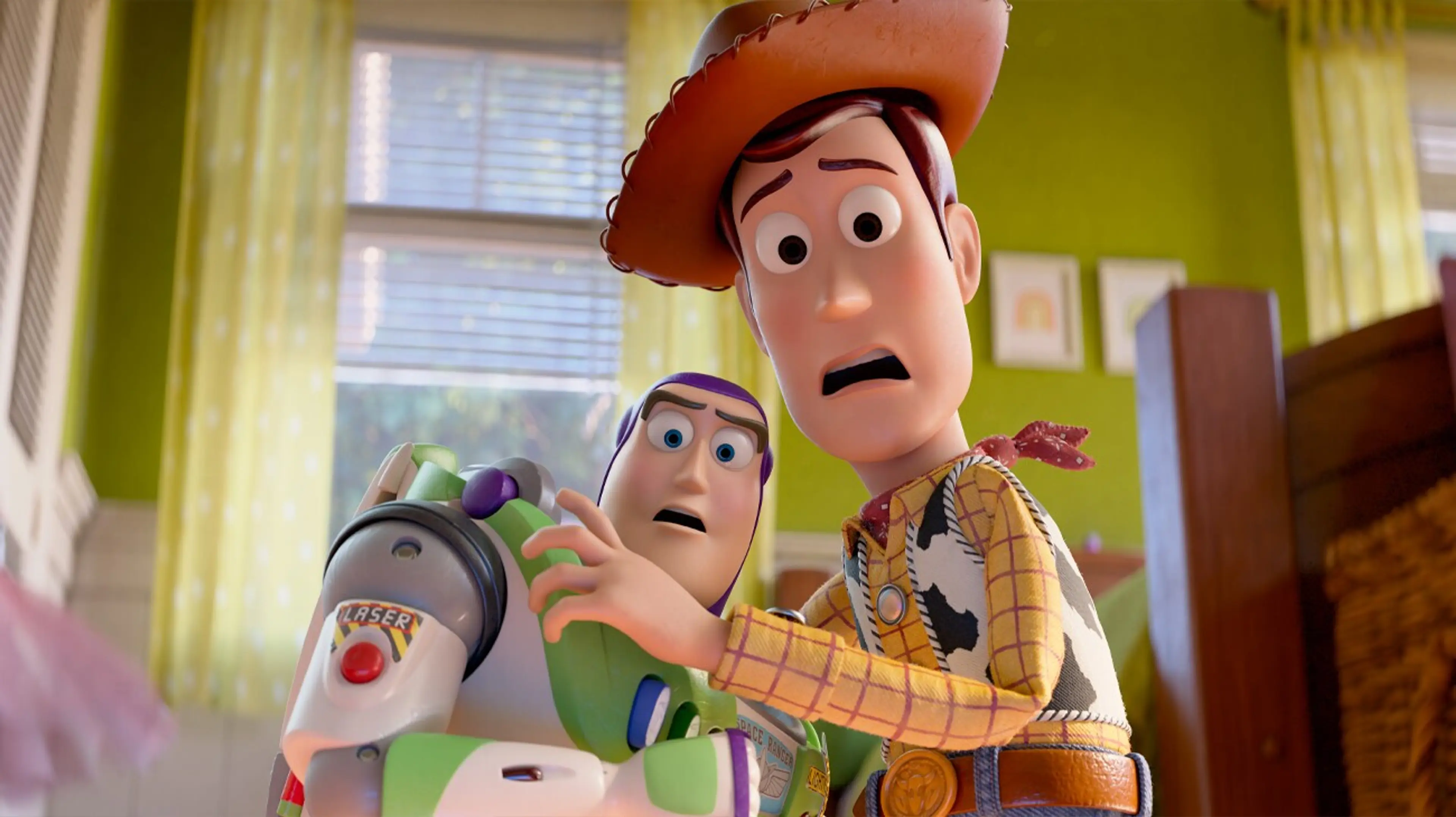Woody holds an arm across Buzz while both look startled in a bedroom.