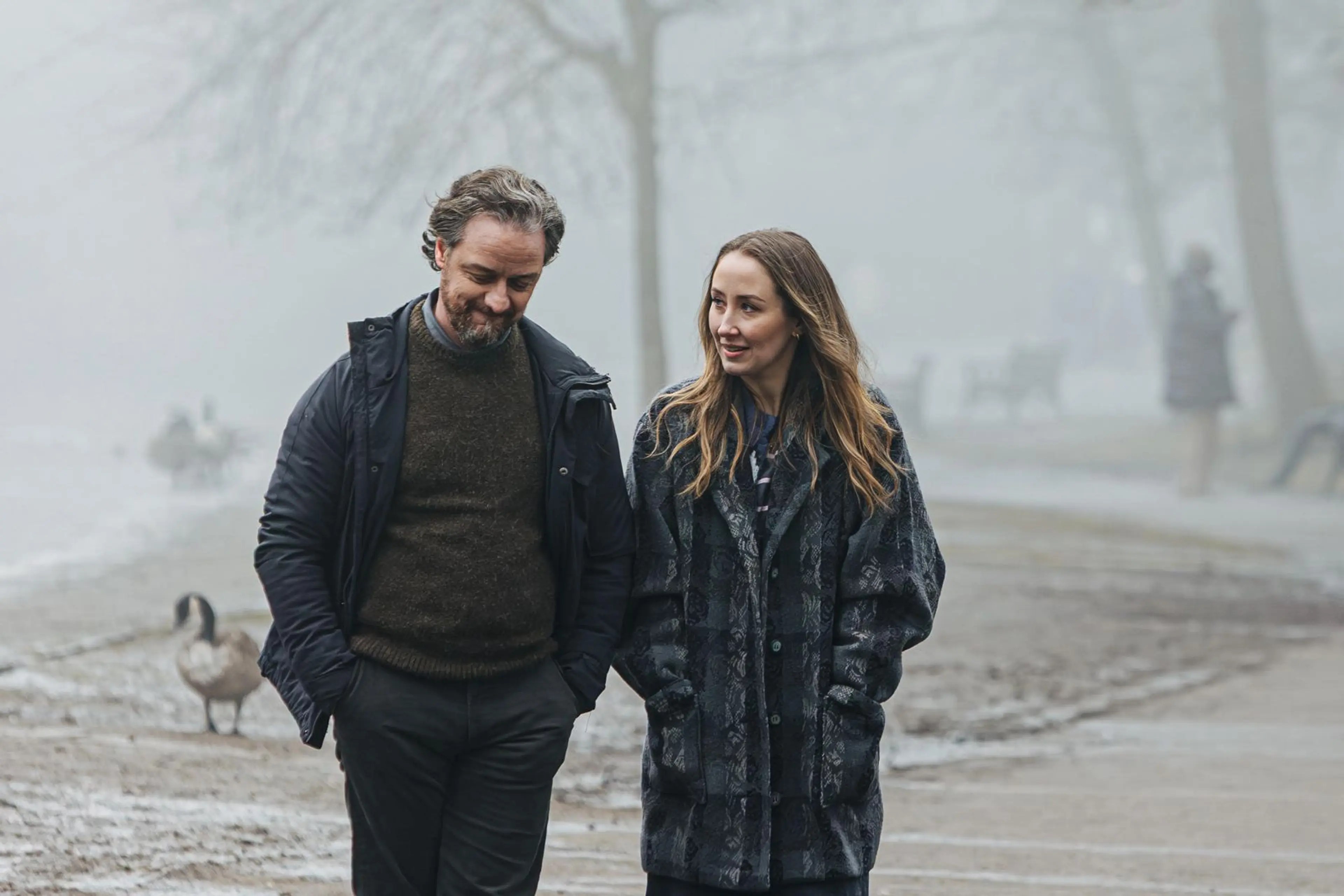James McAvoy and Erin Doherty walk together through mist in the film Faith.
