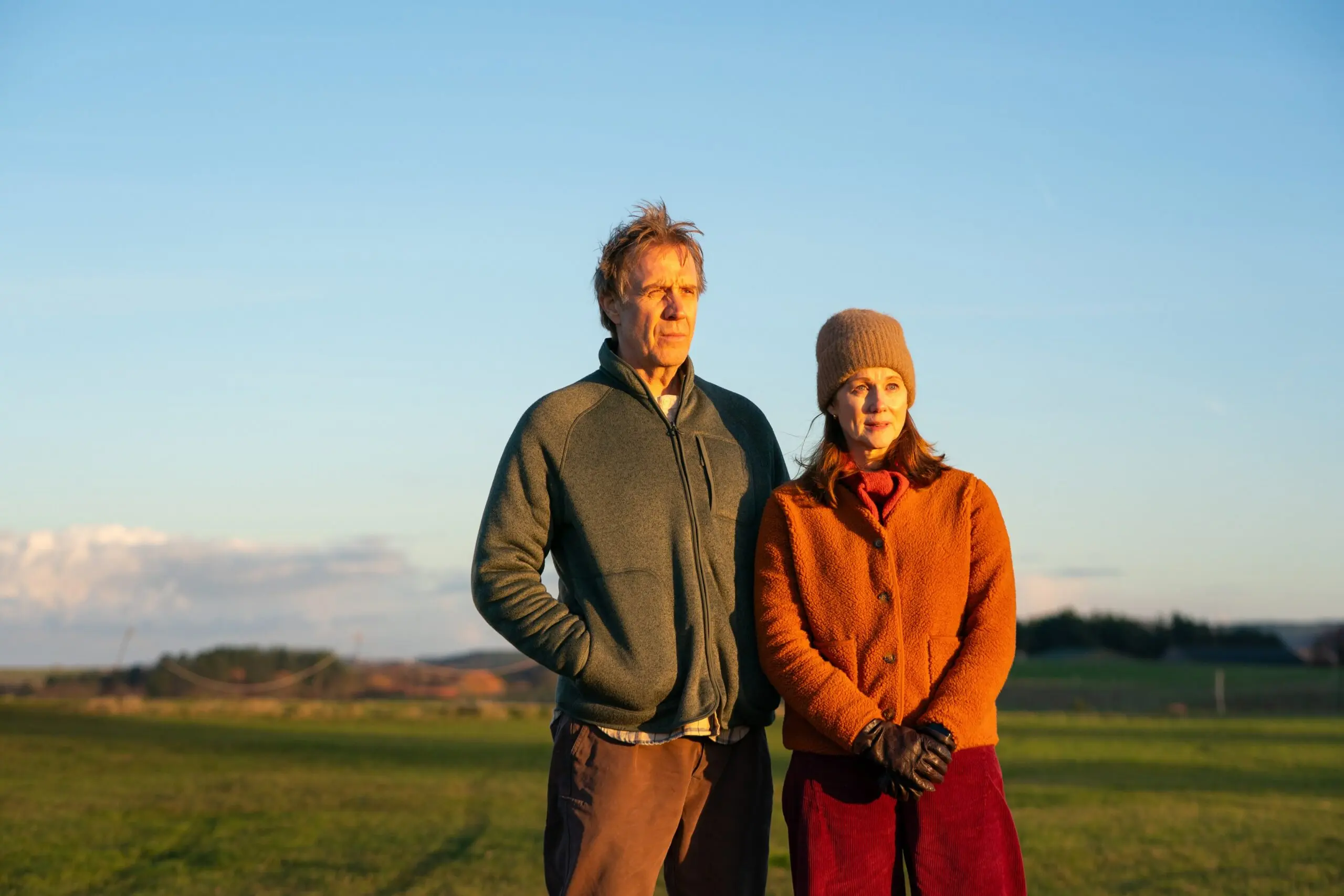 Rhys Ifans as Tony stands beside Monica Dolan as Liz outdoors in Onwards and Sideways.