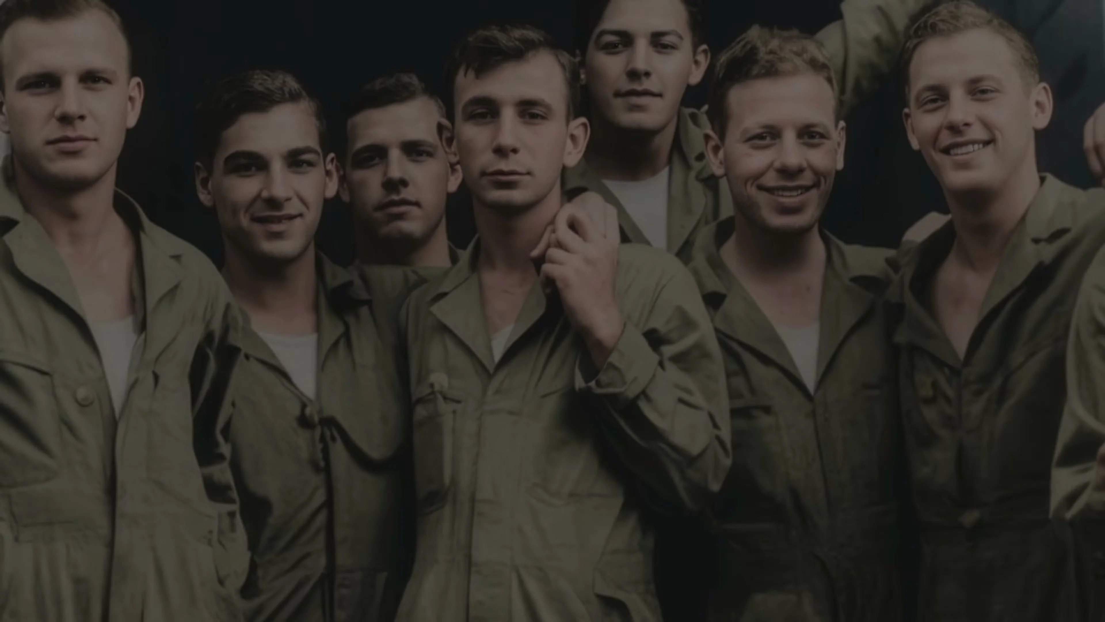 A group of young Band of Brothers cast members stand together in an archival image shown in the Legacy trailer.