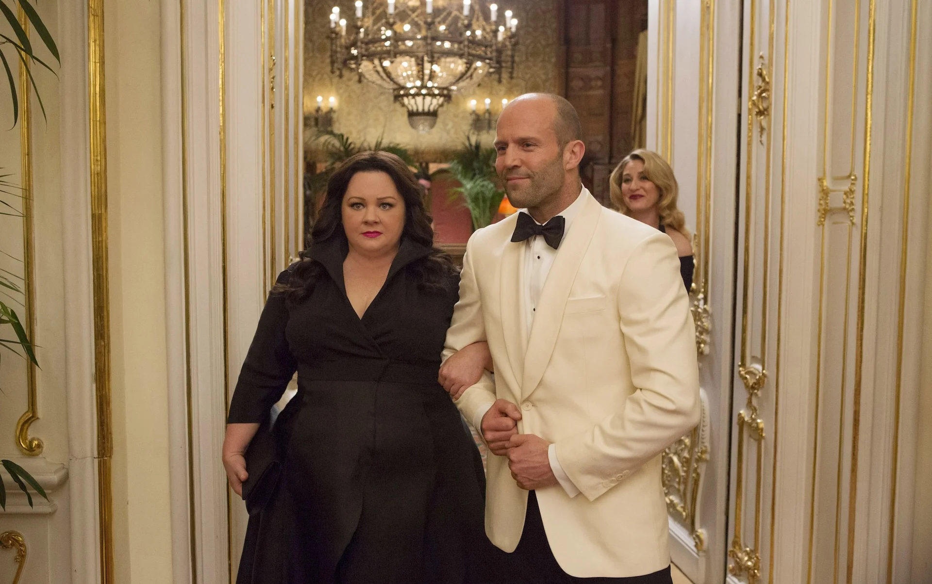 Melissa McCarthy and Jason Statham walk through an ornate room in Spy.