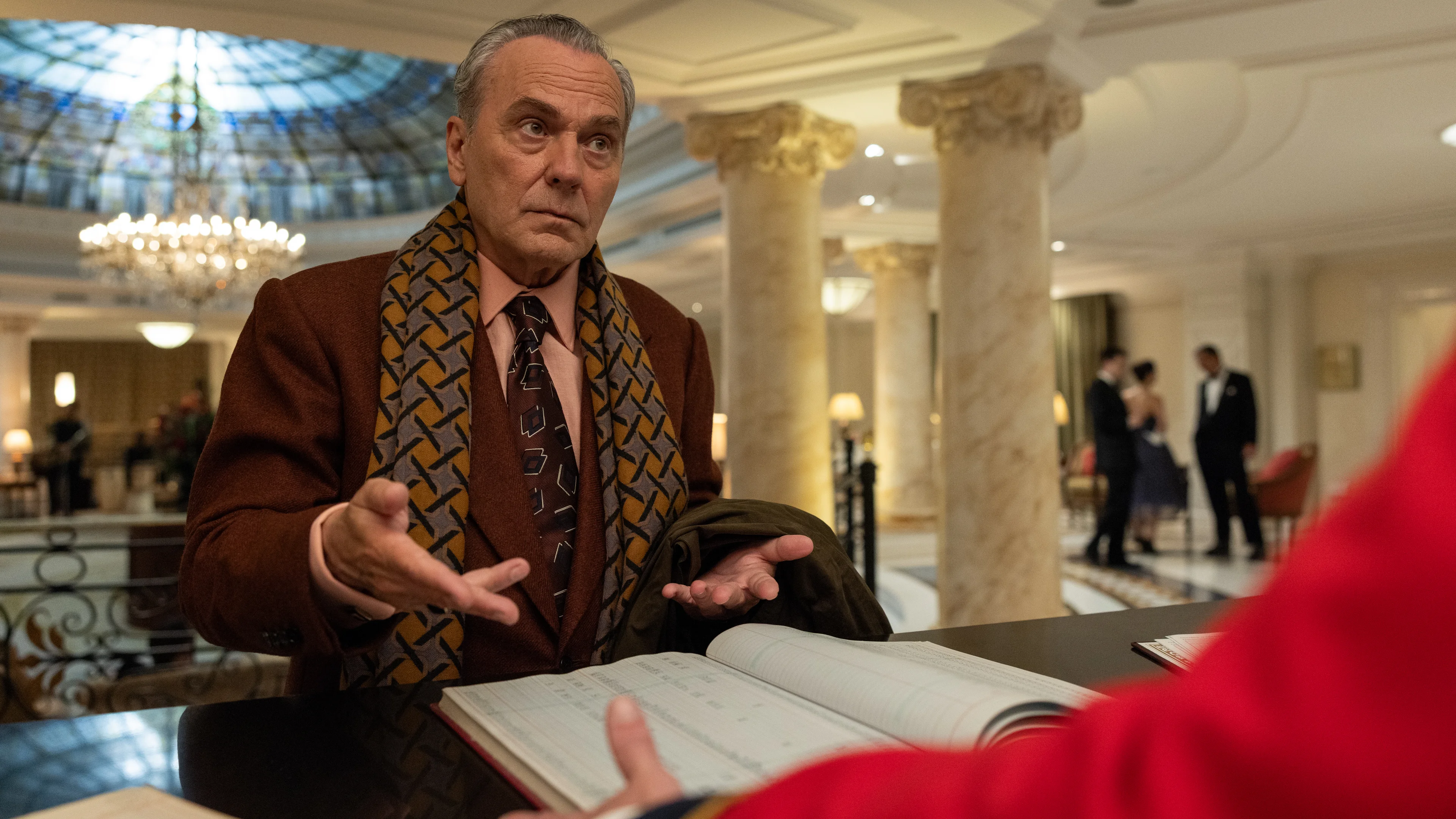 A gray-haired man studies a ledger inside the hotel in Netflix’s The Final Problem.