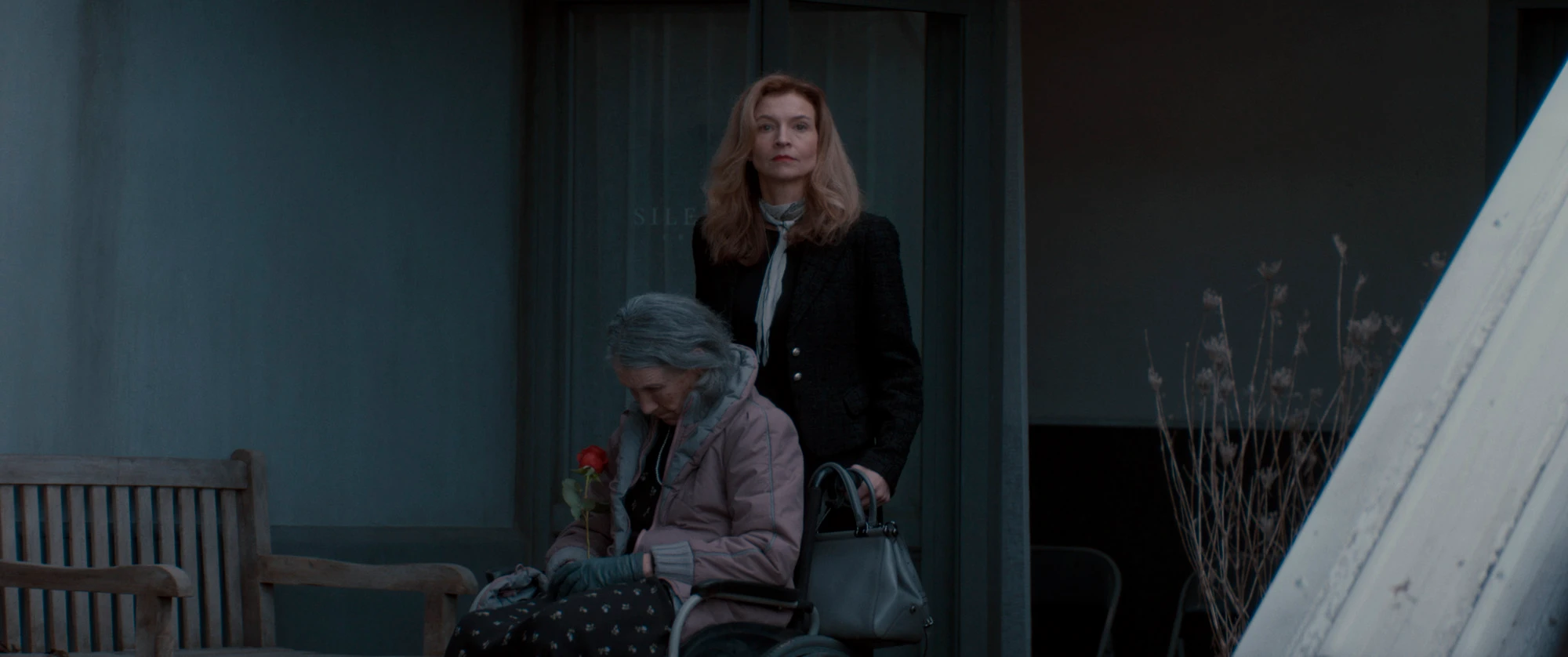 Two women stand outside a home in an Evil Dead Burn still.