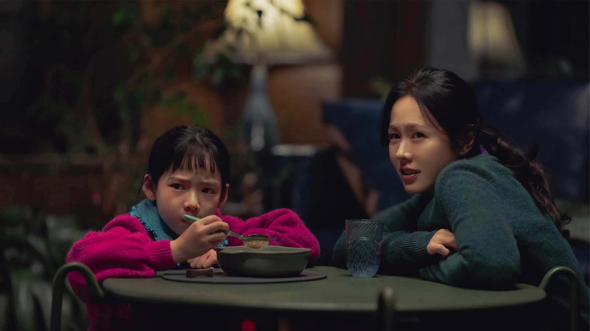 Mi-ri and her daughter sit together at a table in No Other Choice.