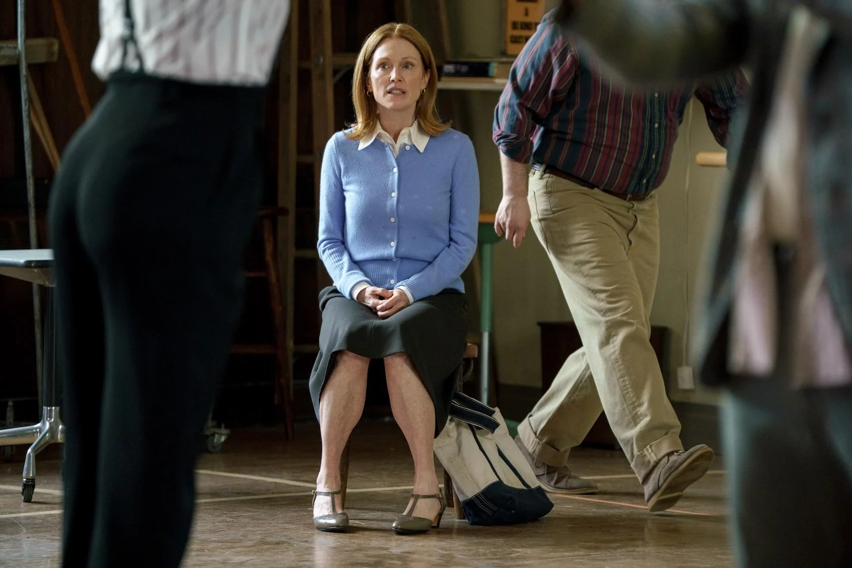 Julianne Moore as Mona sits on a chair while other performers move around her during rehearsal in The Debut.