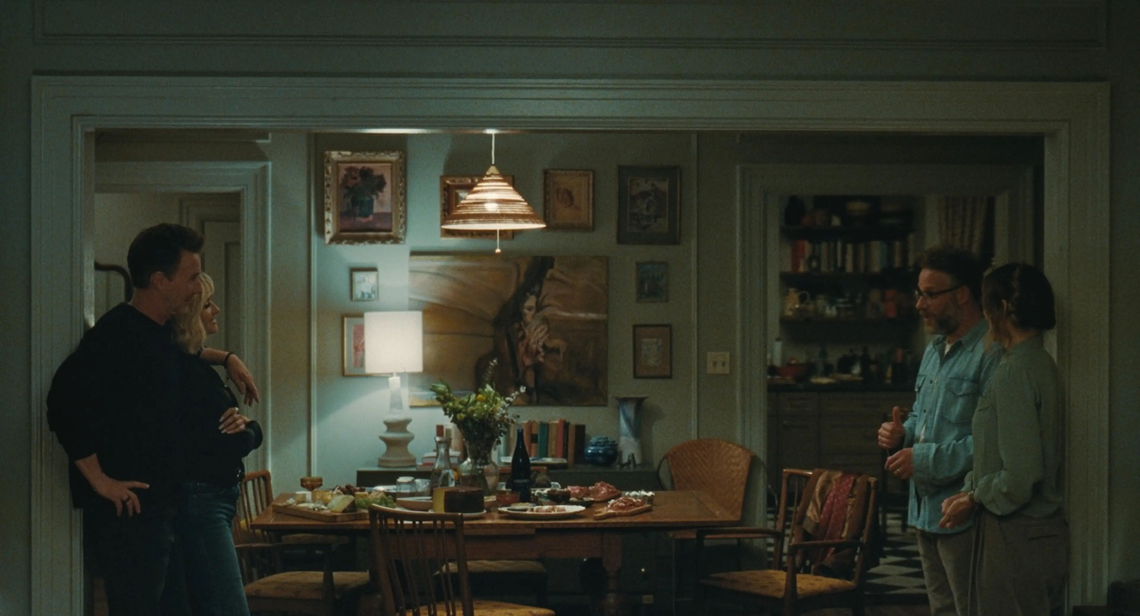 The two couples stand beside a dining table set with food and drinks.