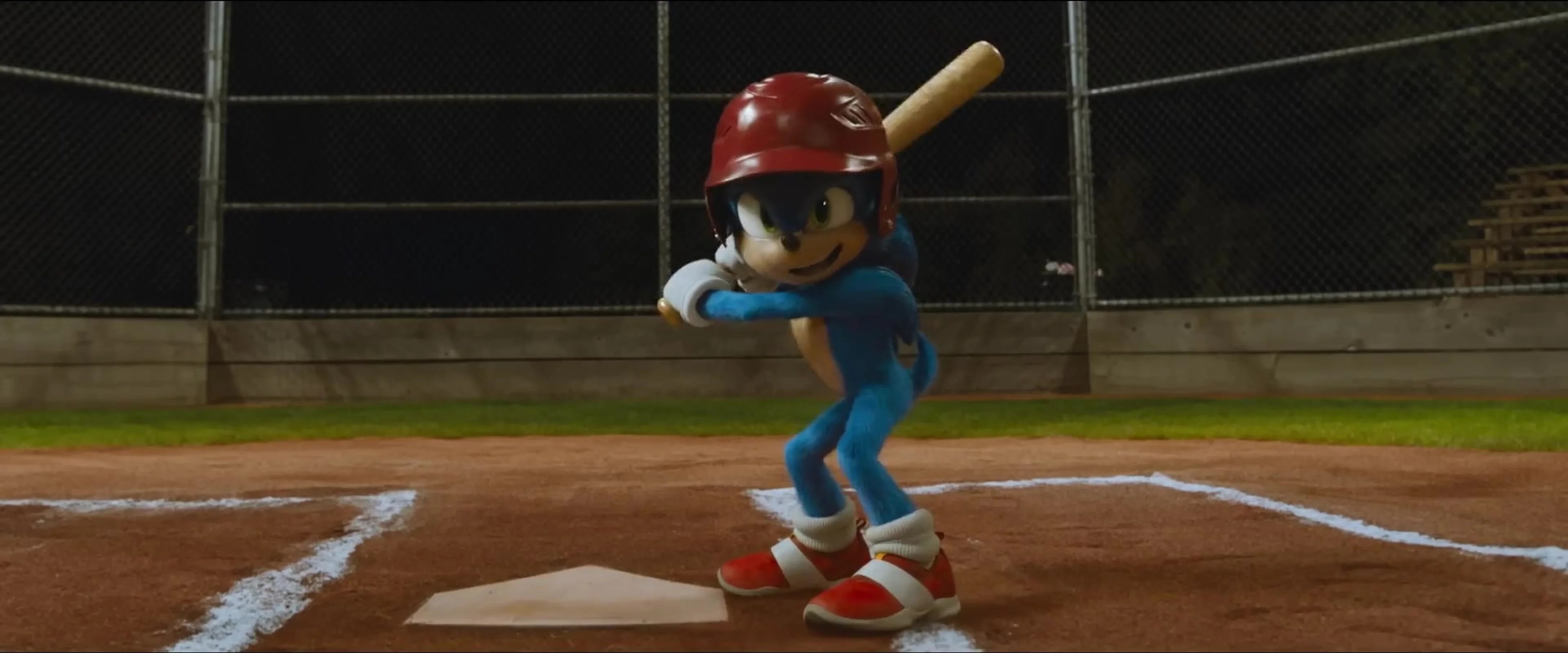 Sonic wears a red batting helmet and holds a baseball bat at home plate in Sonic the Hedgehog.