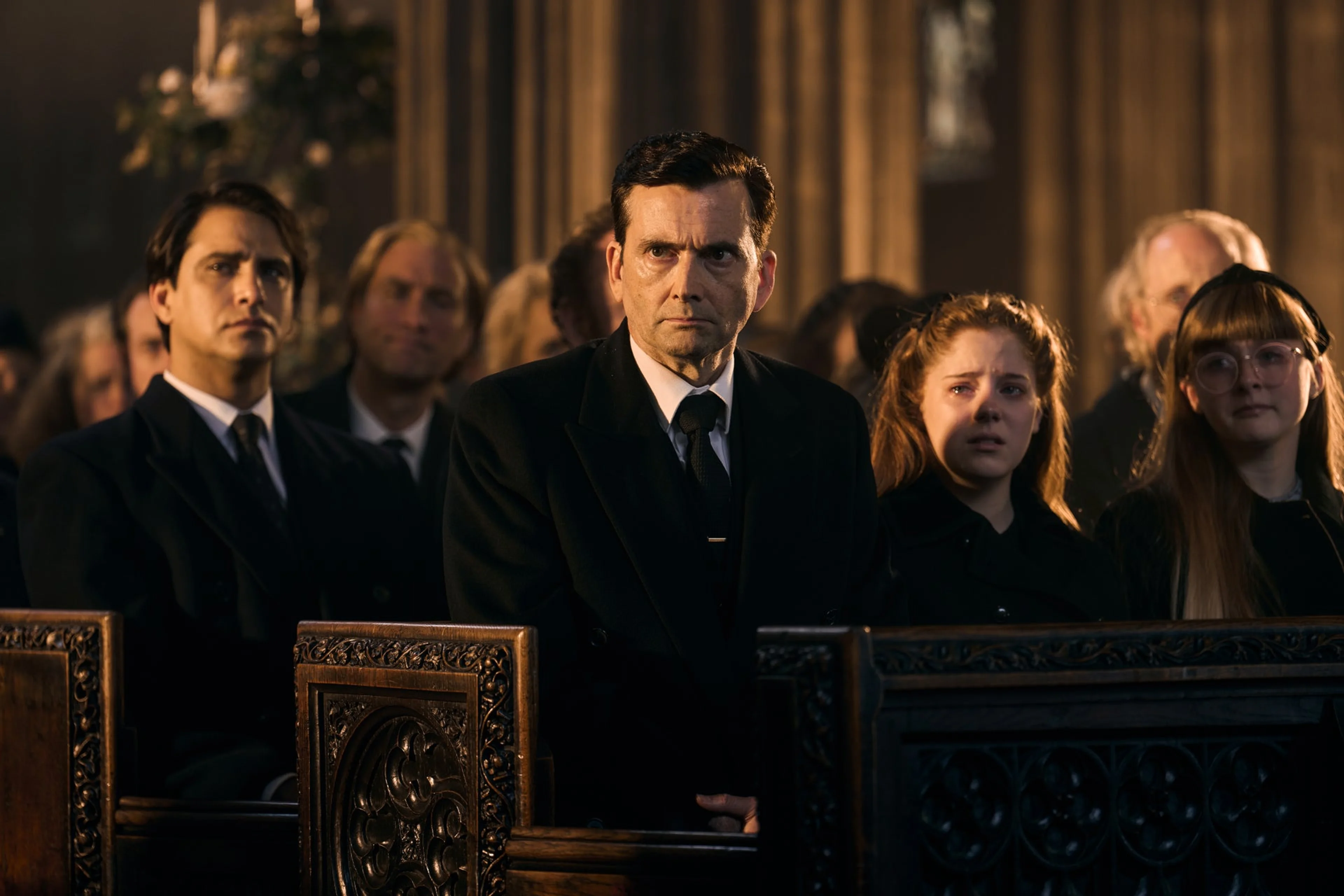 David Tennant as Tony Baddingham sits among other characters in a dark Rivals Season 2 scene.