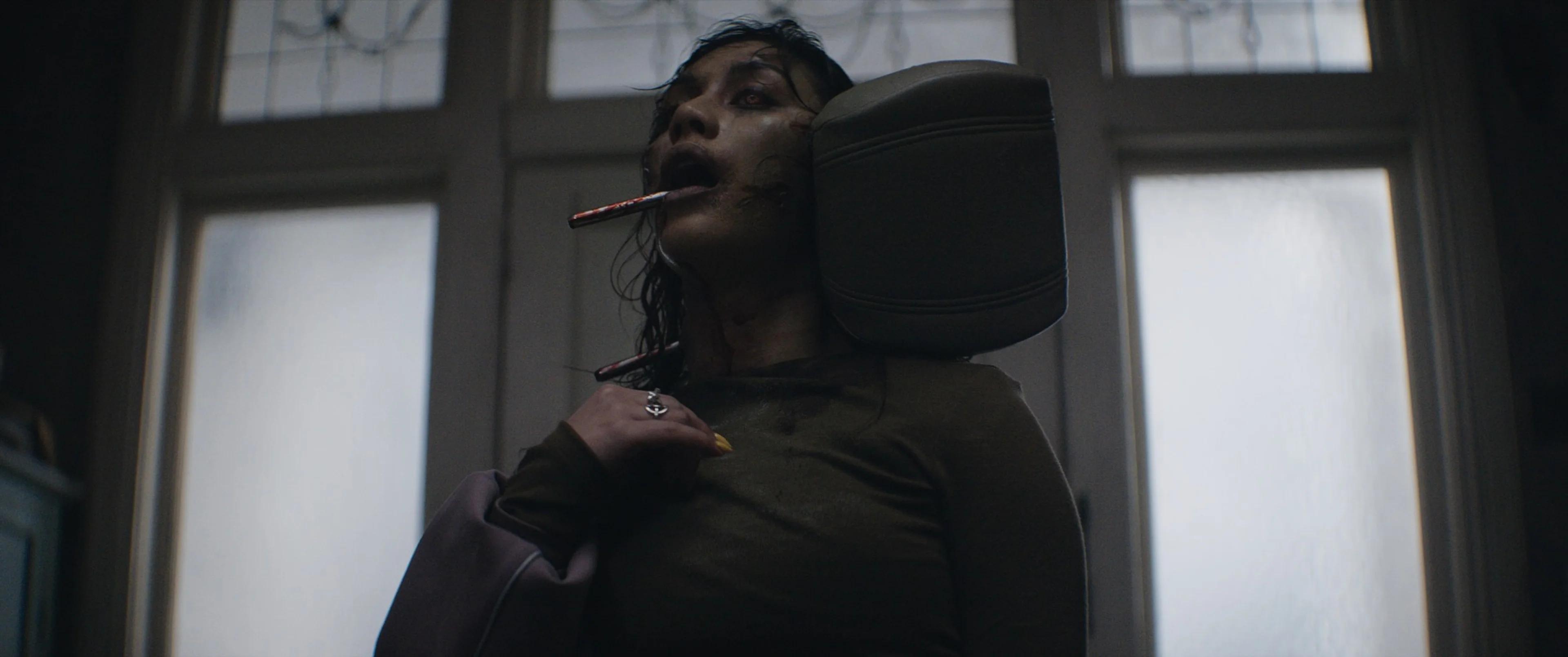 Luciane Buchanan as the possessed Thya, with a car headrest beside her neck.