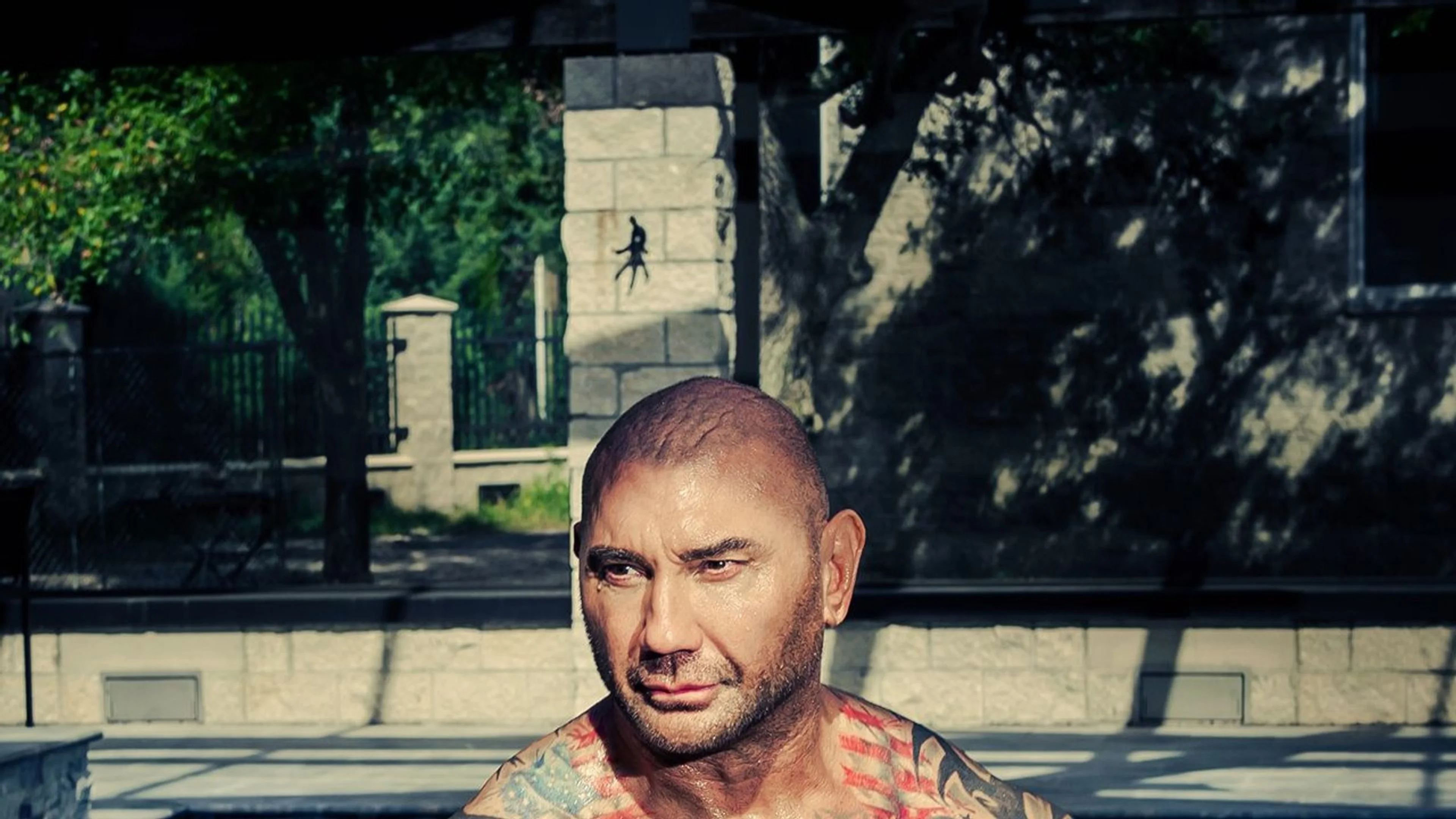 Dave Bautista sits outdoors during a British GQ portrait session.