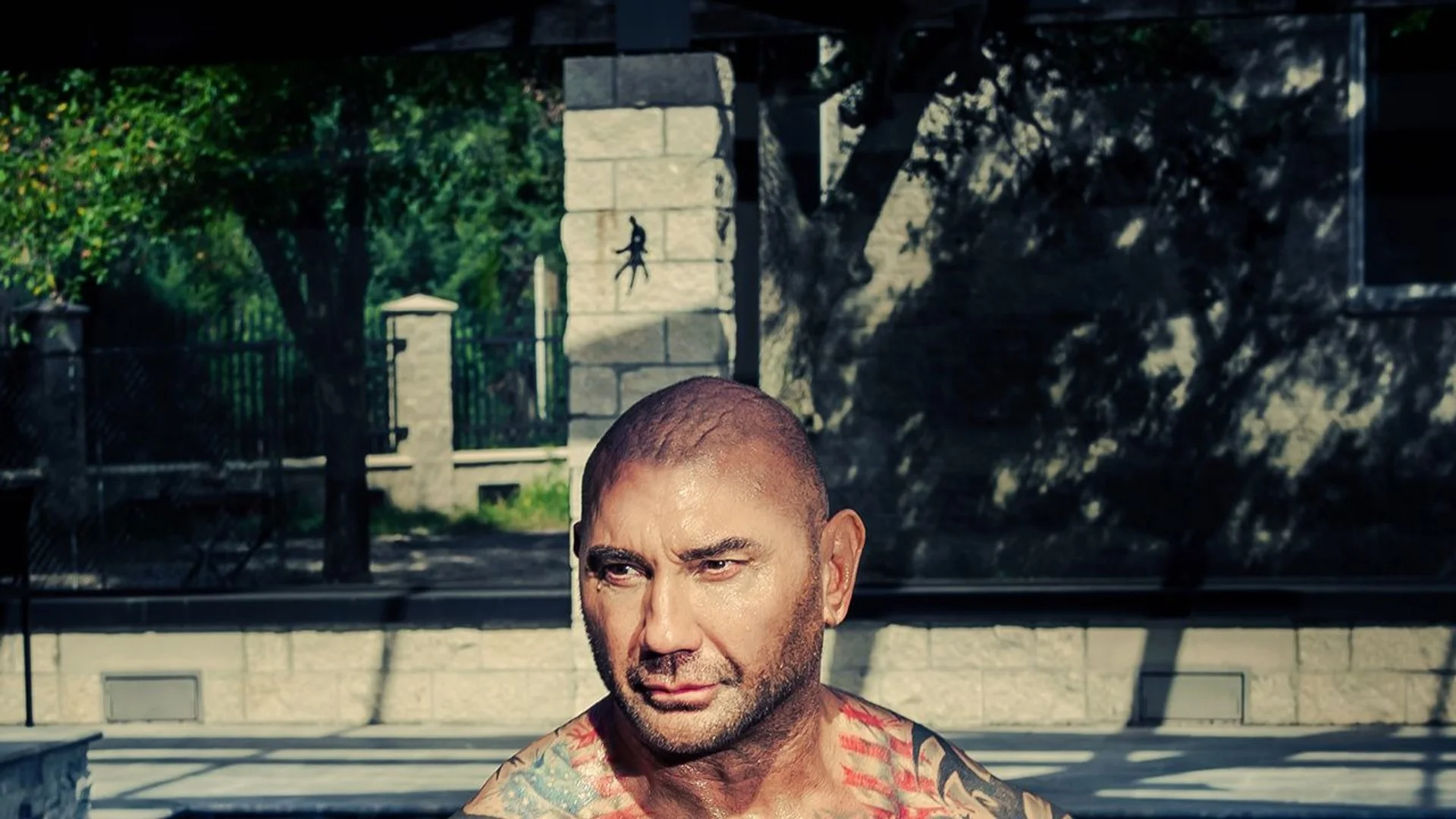 Dave Bautista sits outdoors during a British GQ portrait session.