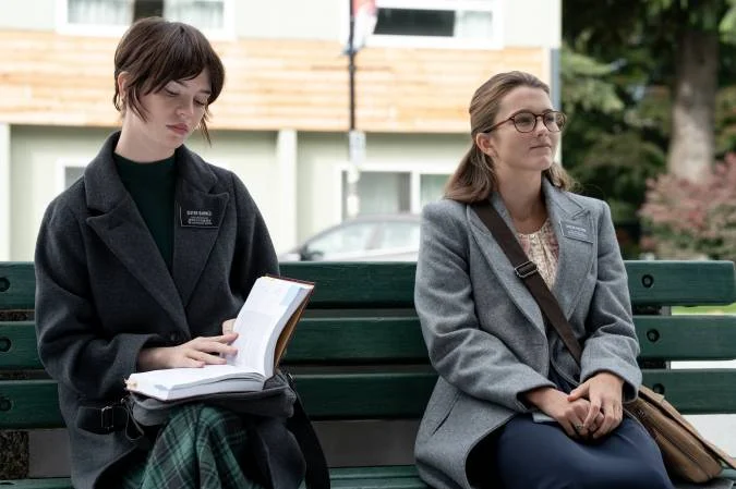 Sister Barnes and Sister Paxton sit side by side, with a book open on Barnes’ lap.