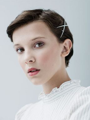 Archive portrait of Millie Bobby Brown with short hair and a white striped blouse.