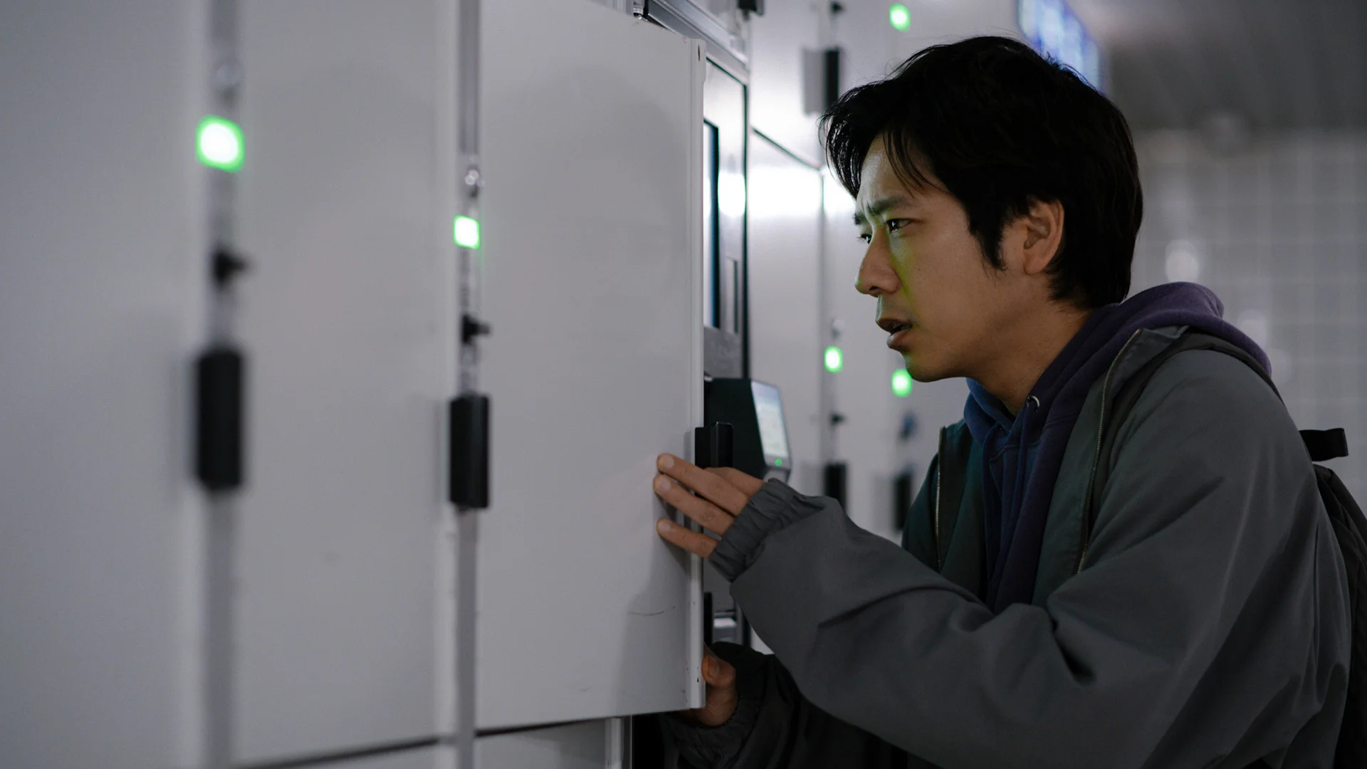 The traveler opens a white locker beside a row of green indicator lights.