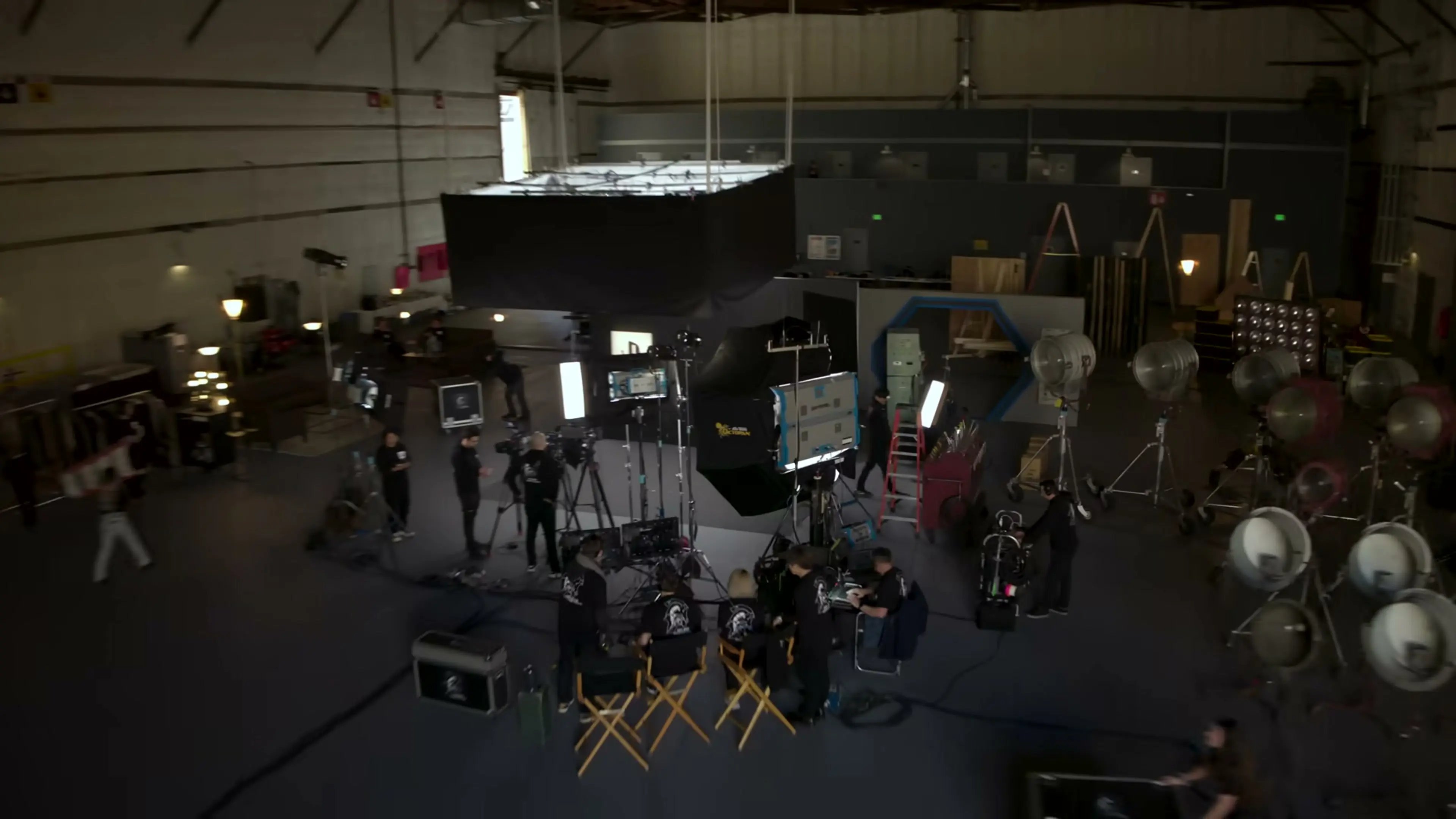 A film-production stage contains cameras, lights, monitors and crew equipment.